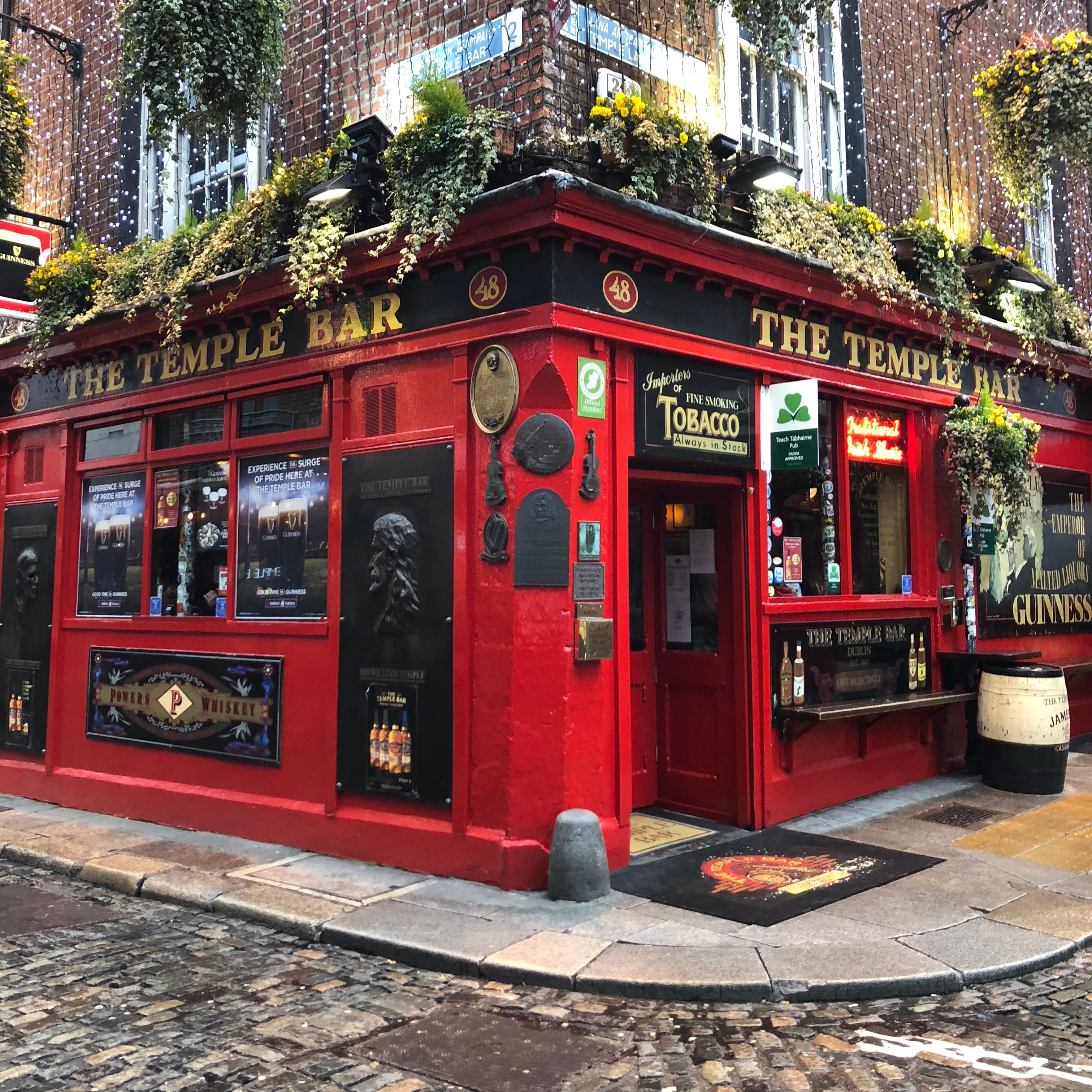 View of The Temple Bar in Dublin during the day, bright red and lined with plants on top