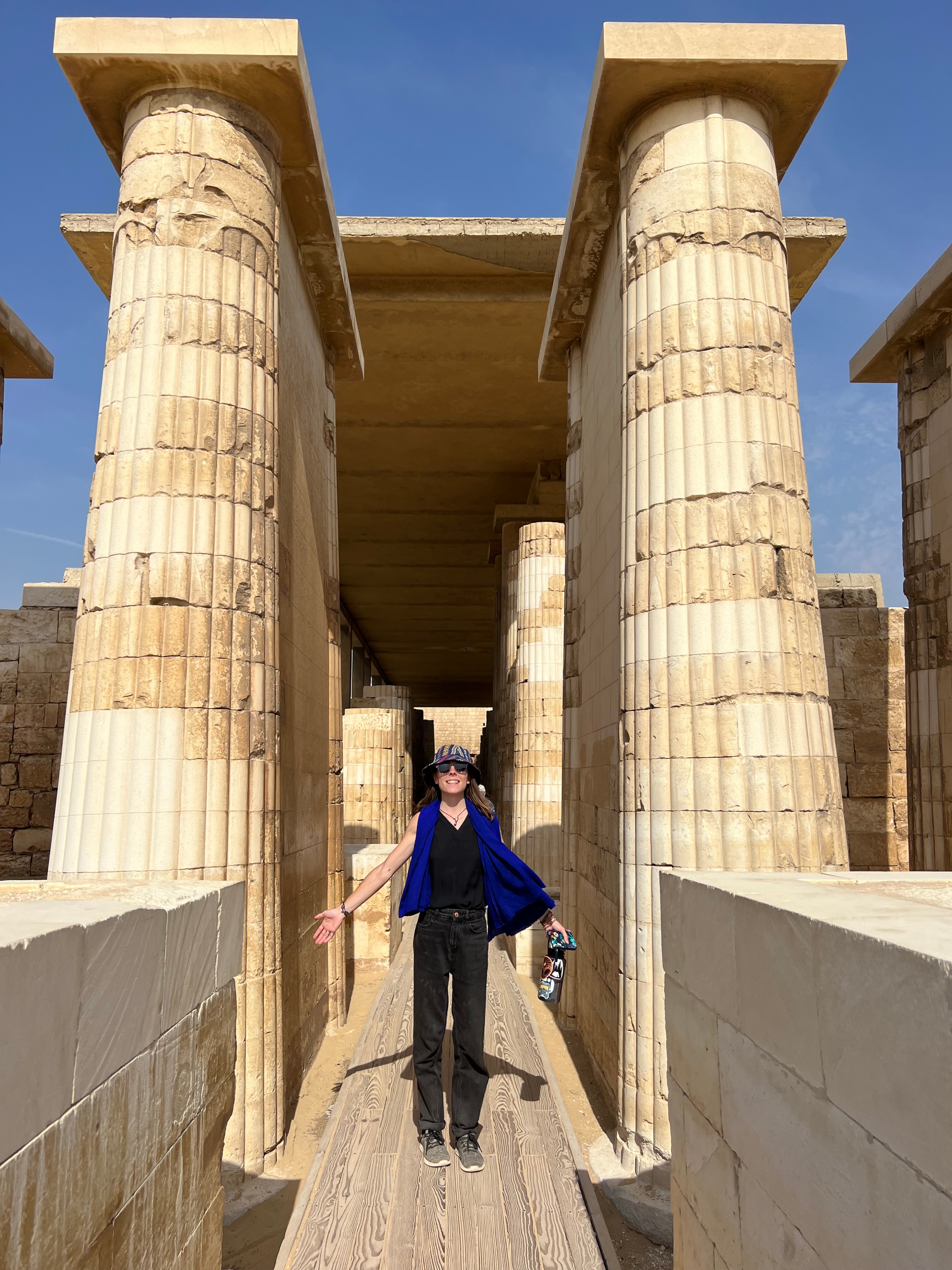 Advisor posing for an image with ancient ruins and columns on a sunny day. 