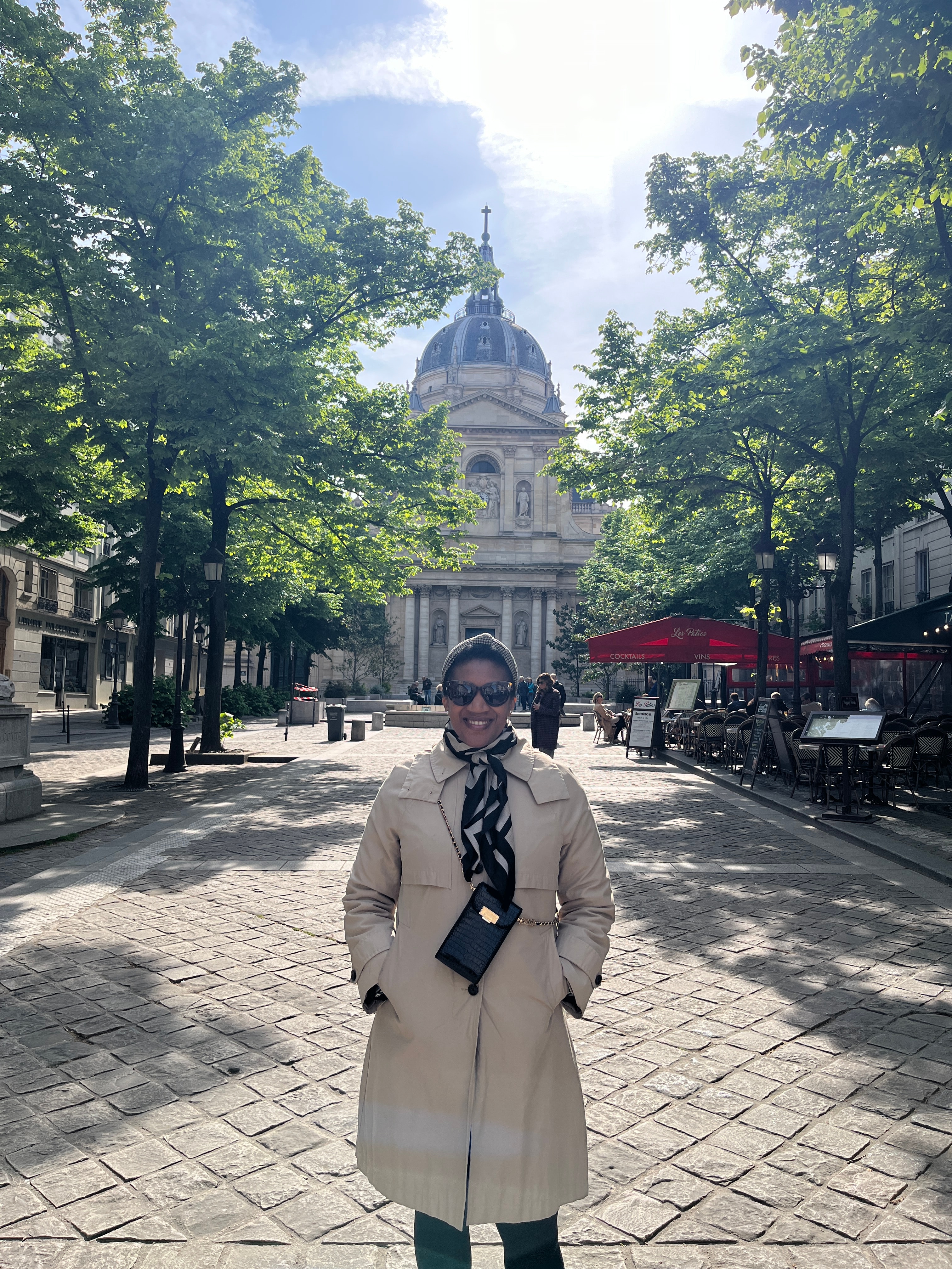 Advisor posing with a classic building in the distance on a sunny day.