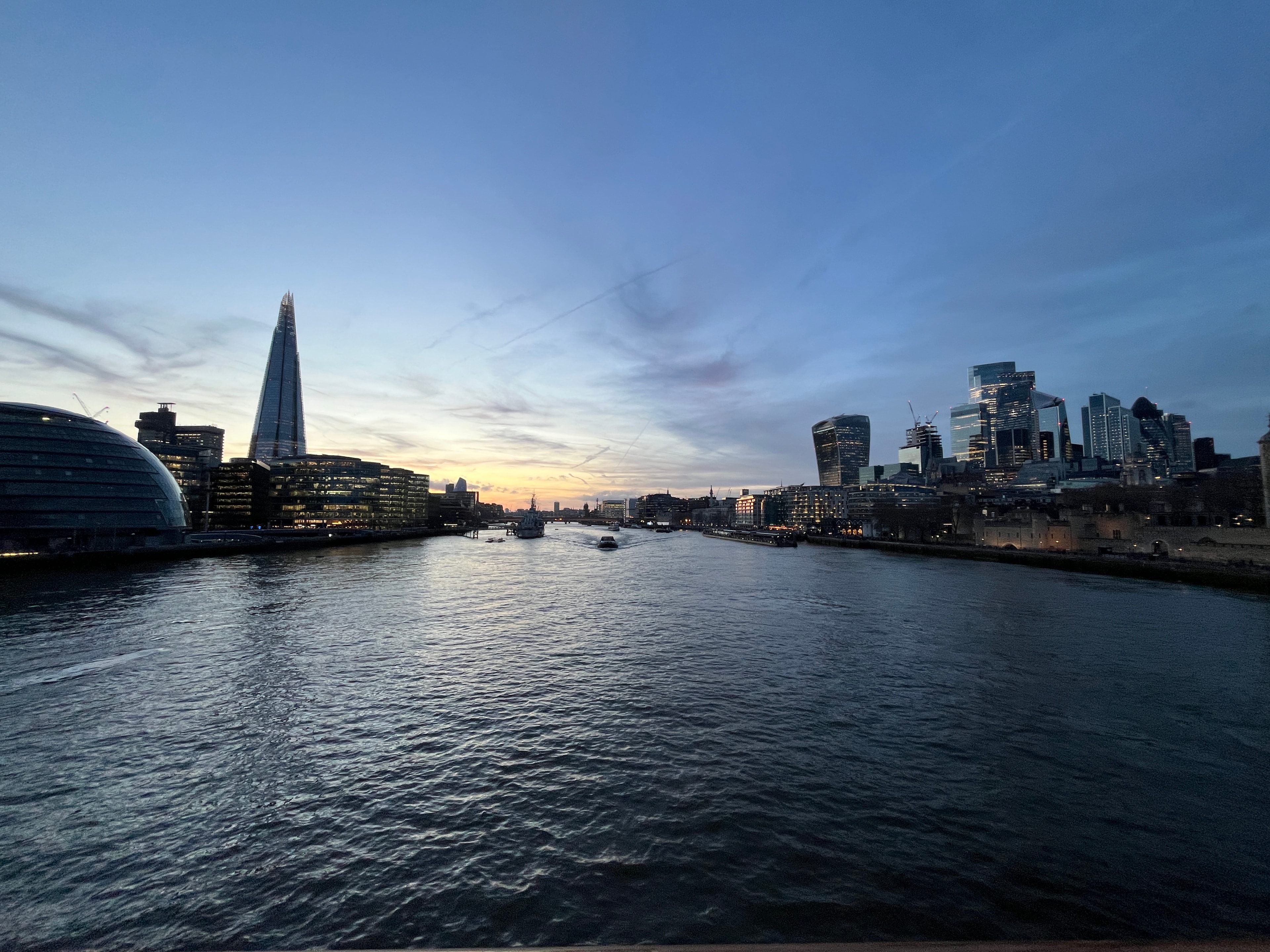 A view of a body of water at sunset with buildings in the distance. 