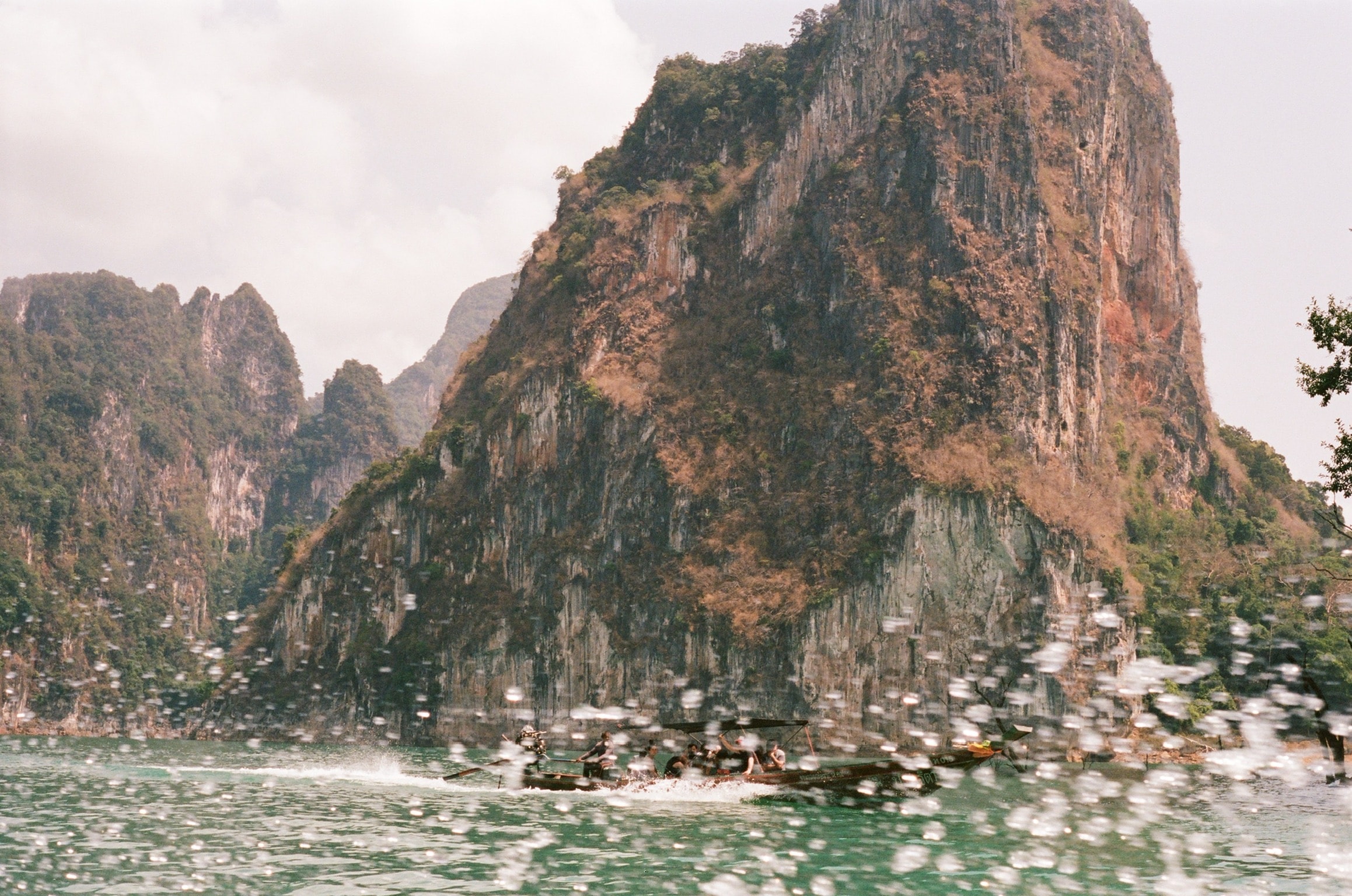 View of rocky cliffs taken from a boat at sea with water splashing in front of the camera