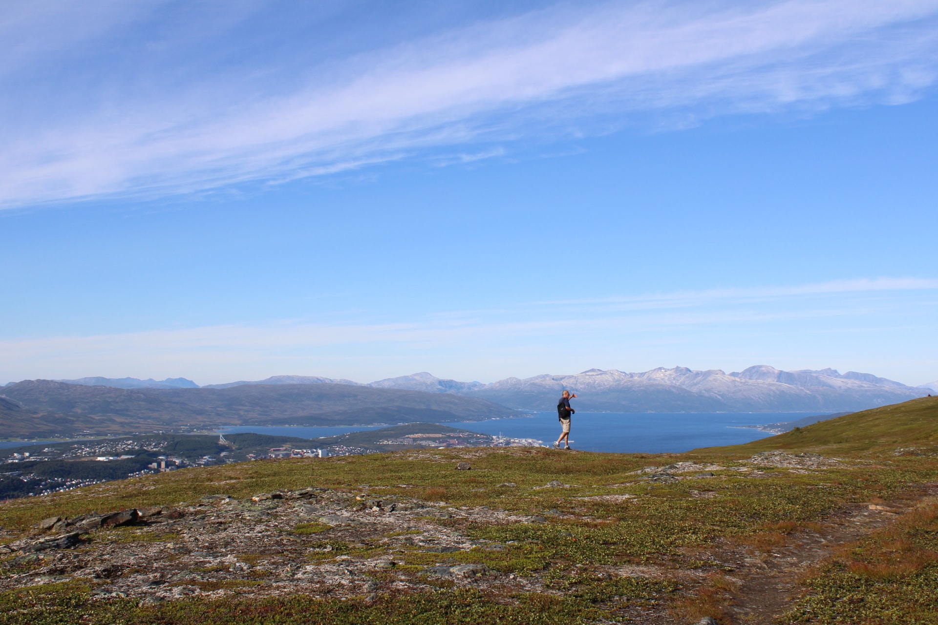 Isabel hiking along a cliff high above sea level with the ocean and mountains visible far in the distance