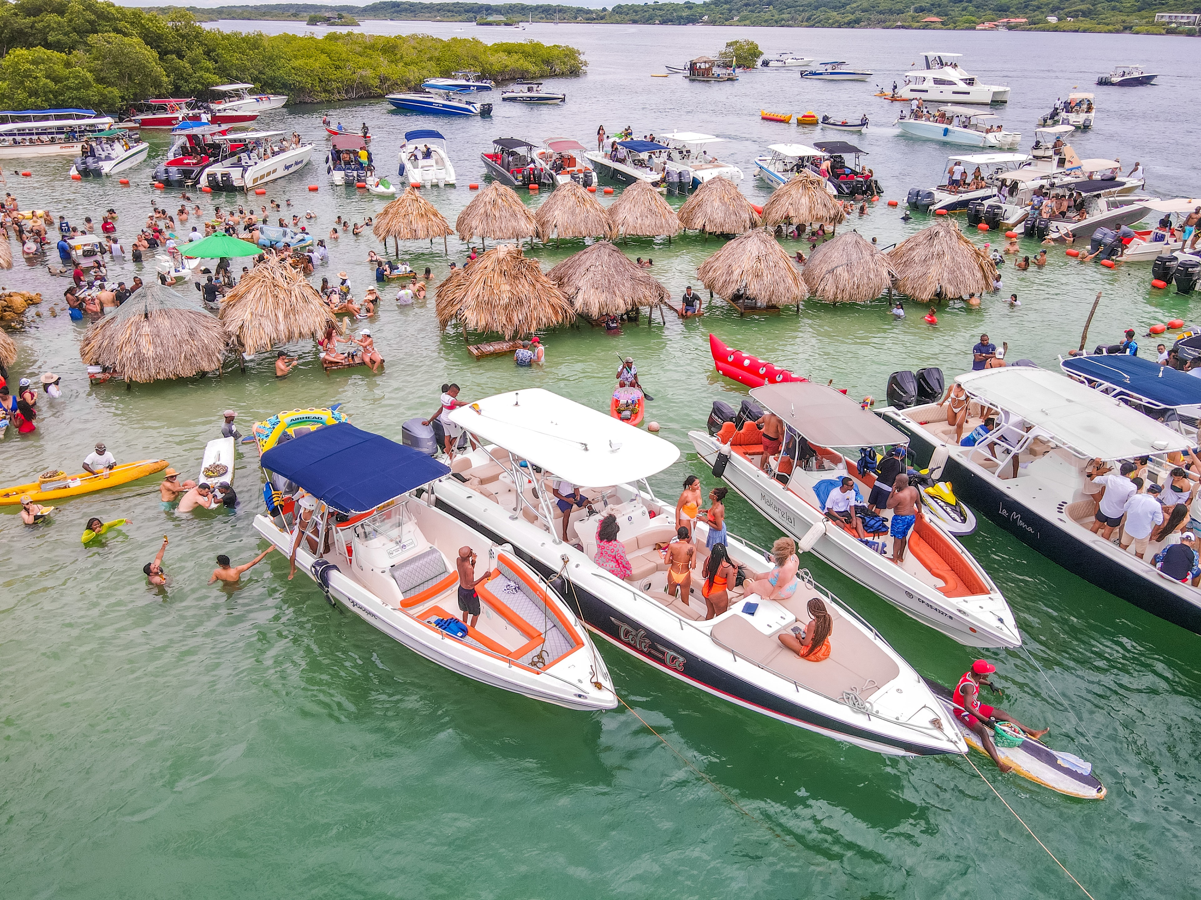 Aerial view of boats and thatched huts with people enjoying themselves in the surrounding water