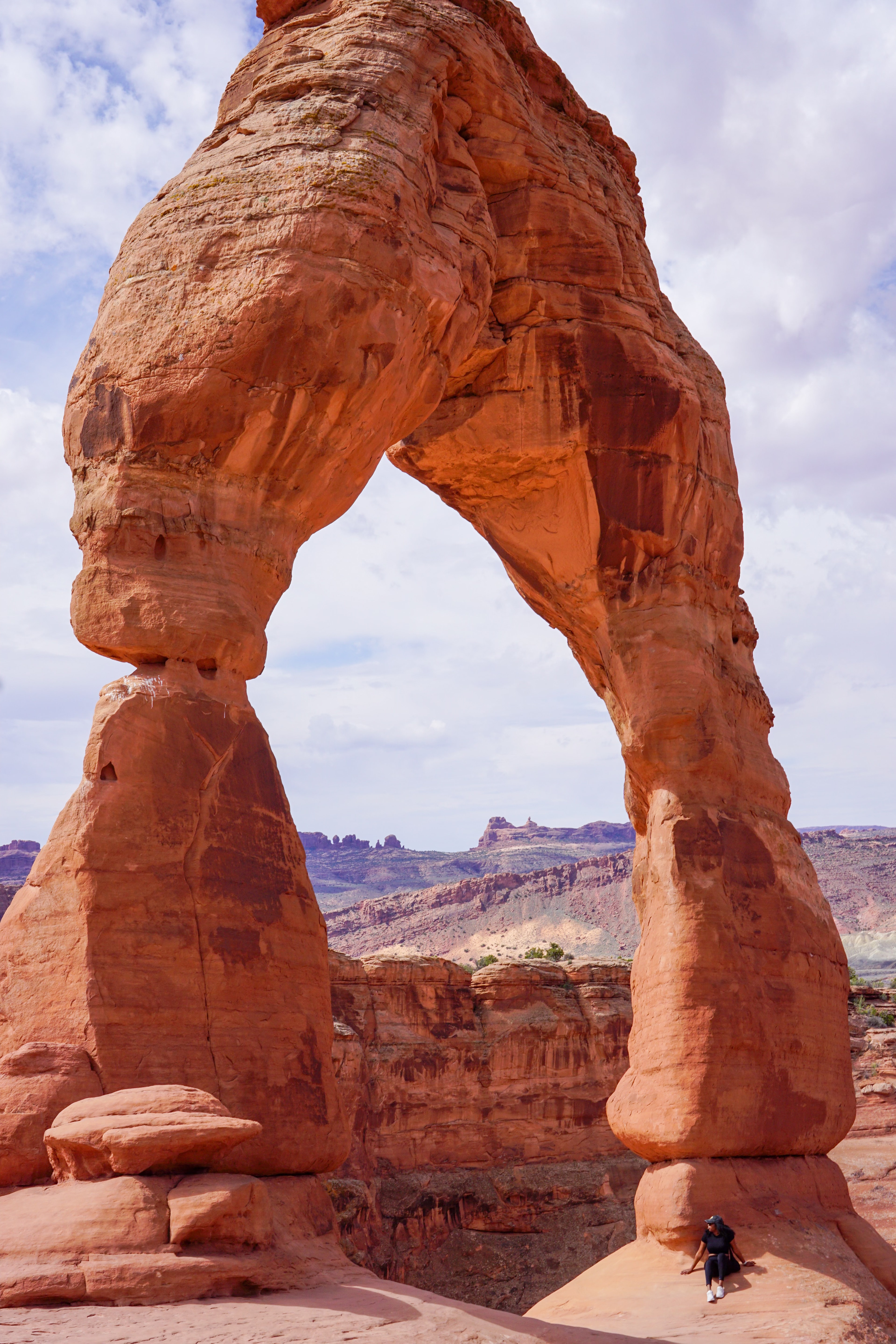 Beautiful view of a red rock arch with more rocky landscape visible behind it on a sunny day