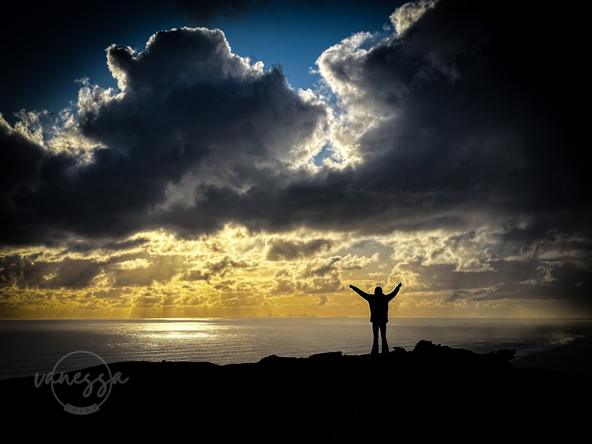 A image during a sunset with an advisor posing in the distance with clouds. 