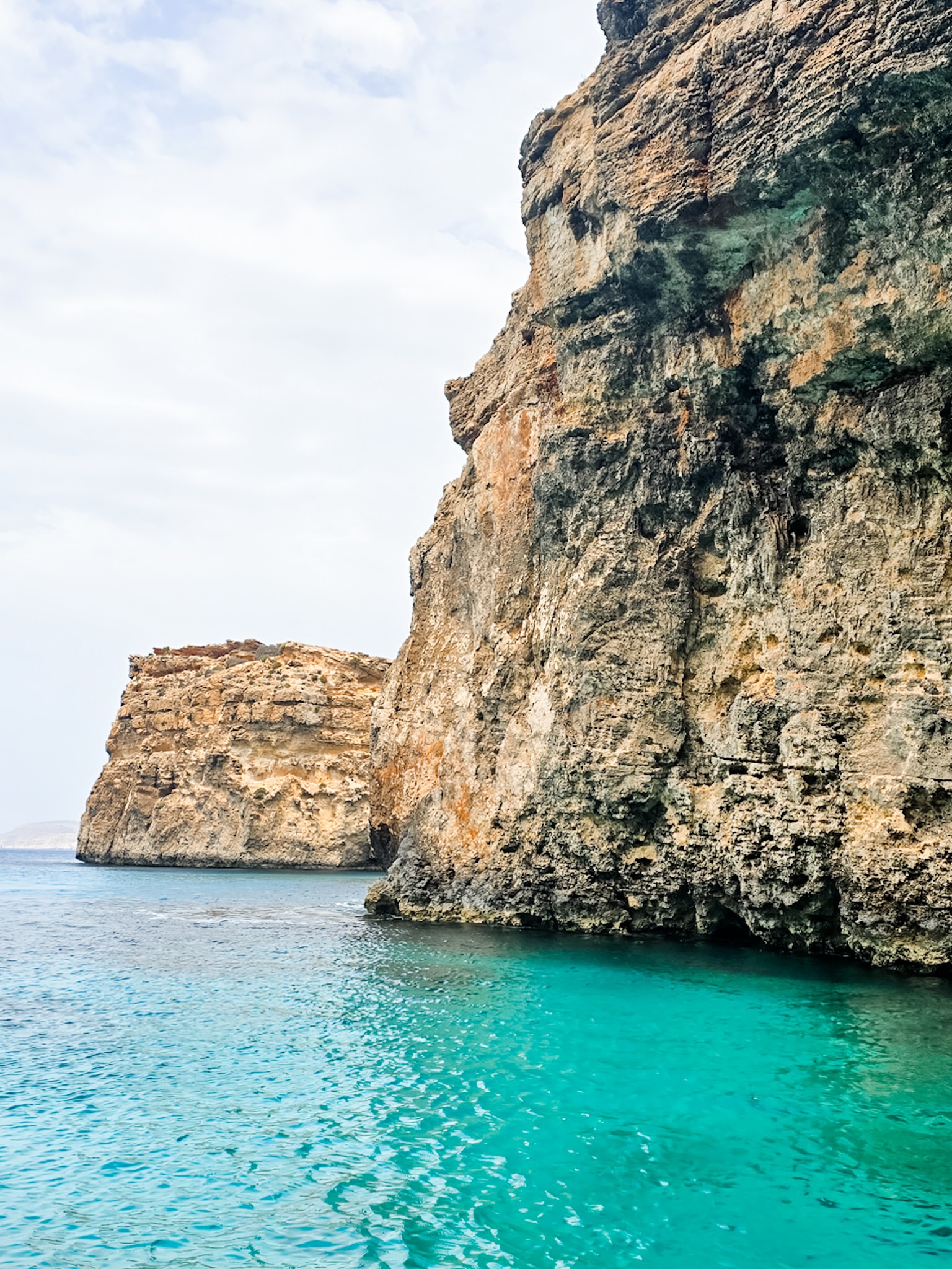 A view of cliffs descending into the ocean on a sunny day.