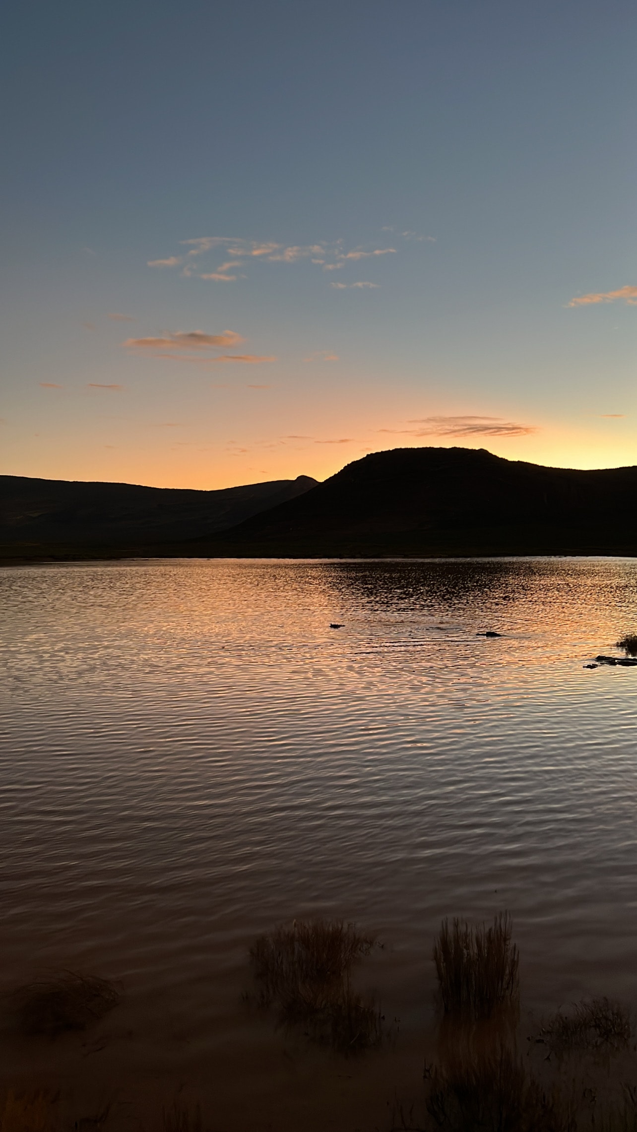 Beautiful view of a serene lake with mountains in the distance during sunset