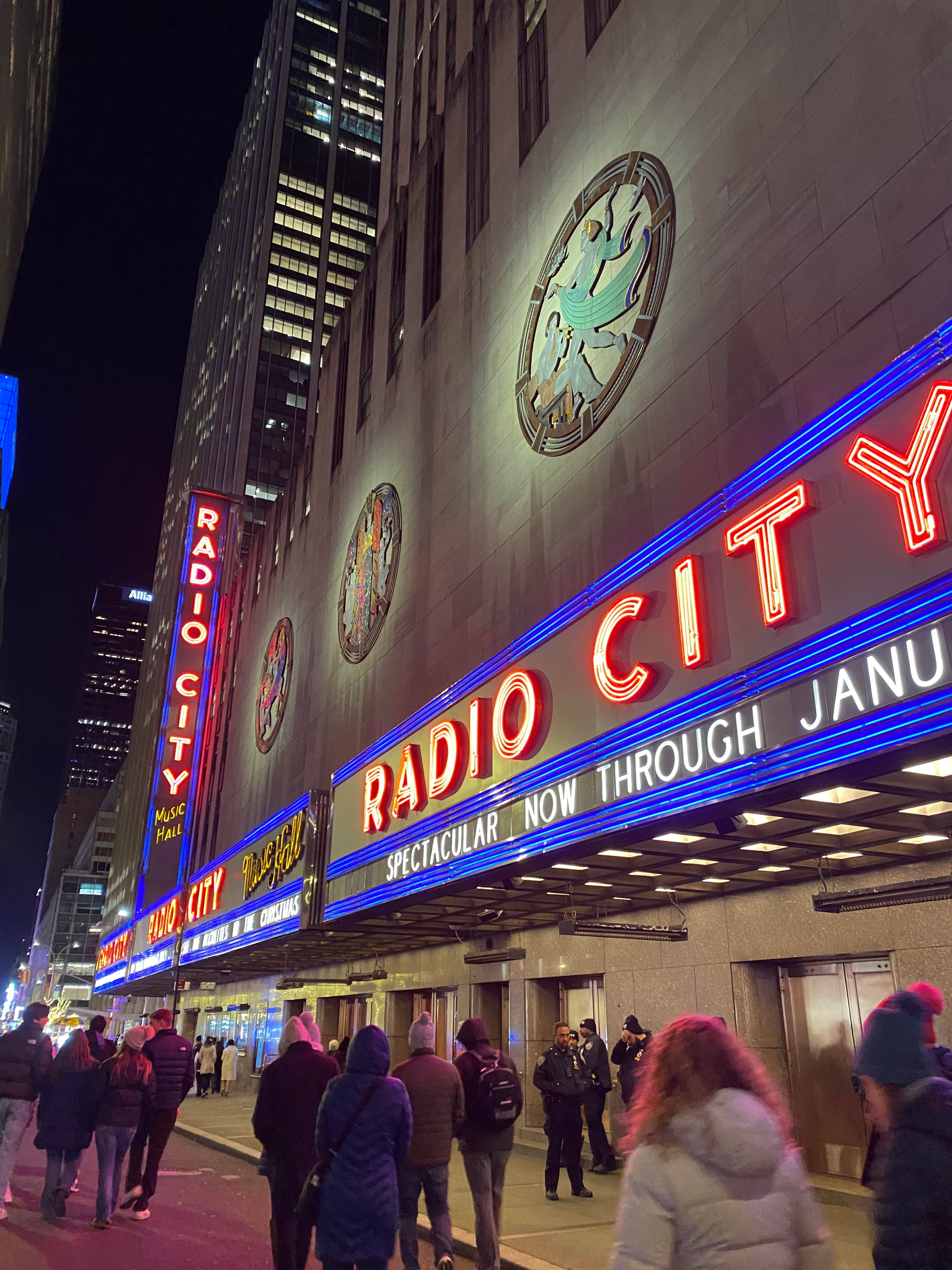 A street view of Radio City Music Hall in New York City at nighttime with the venues iconic lights lit up.