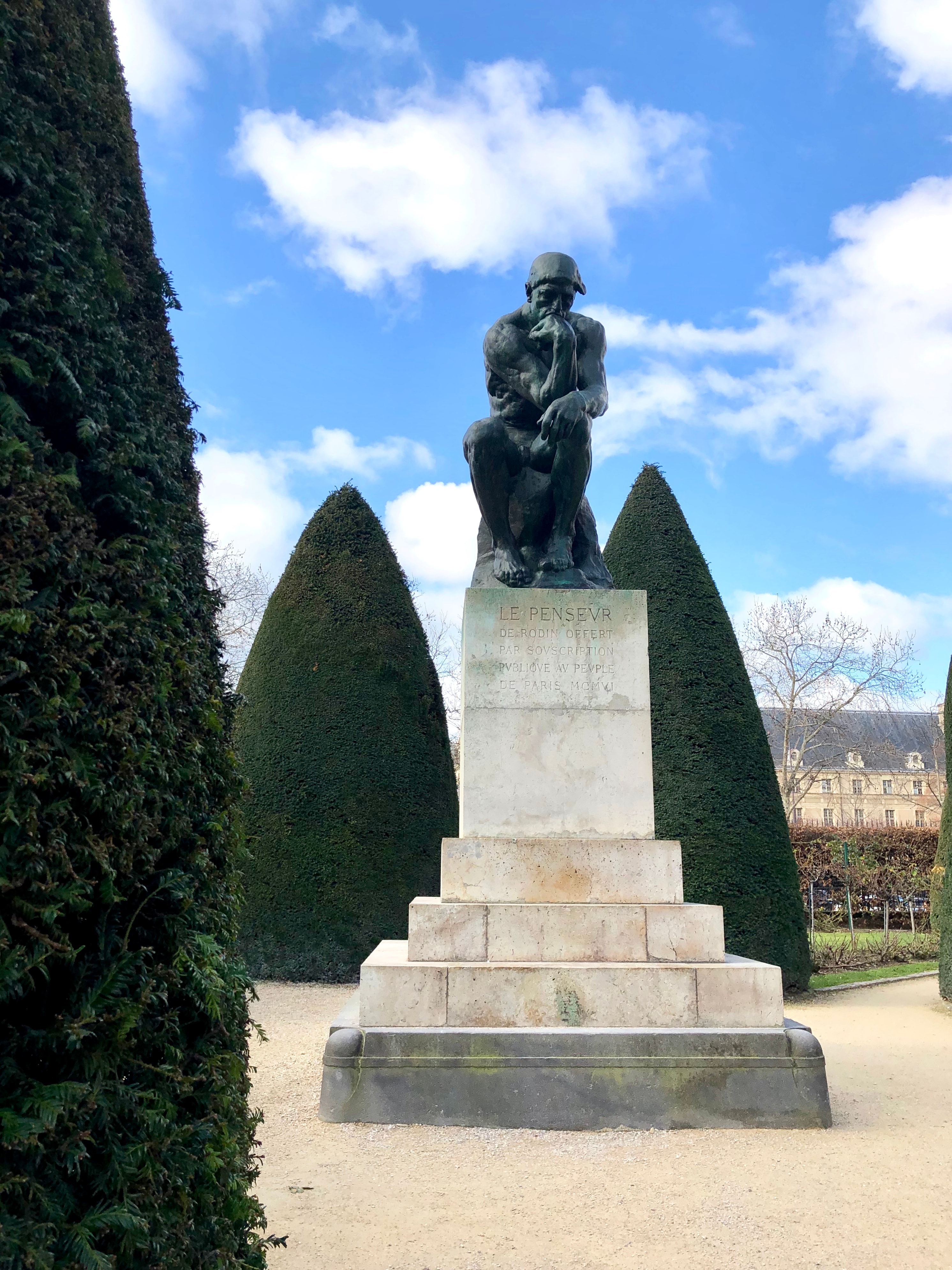 Image of The Thinker statue, the figure of man sitting while resting his head on his hand, on a sunny day