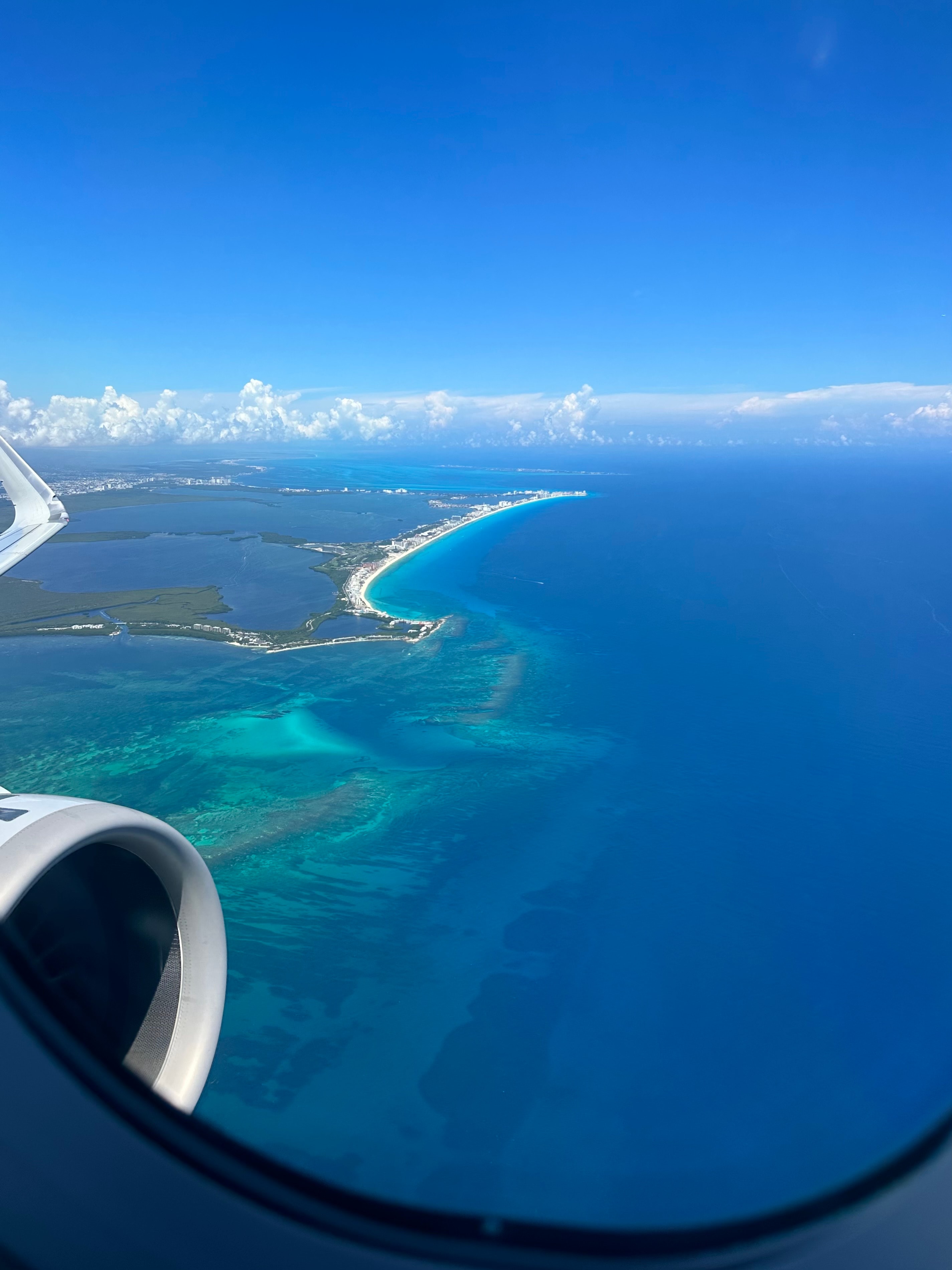 View from an aircraft of clouds and crystal clear waters below on a sunny day. 