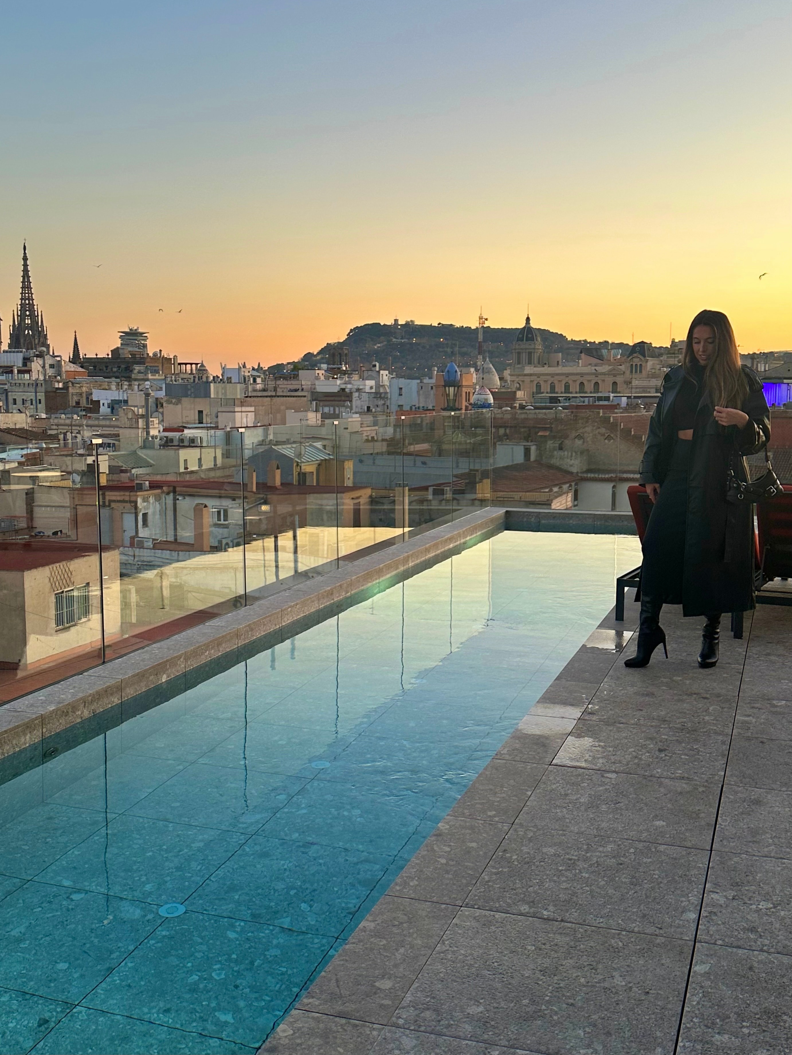 Advisor posing next to a pool overlooking a cityscape at dusk. 