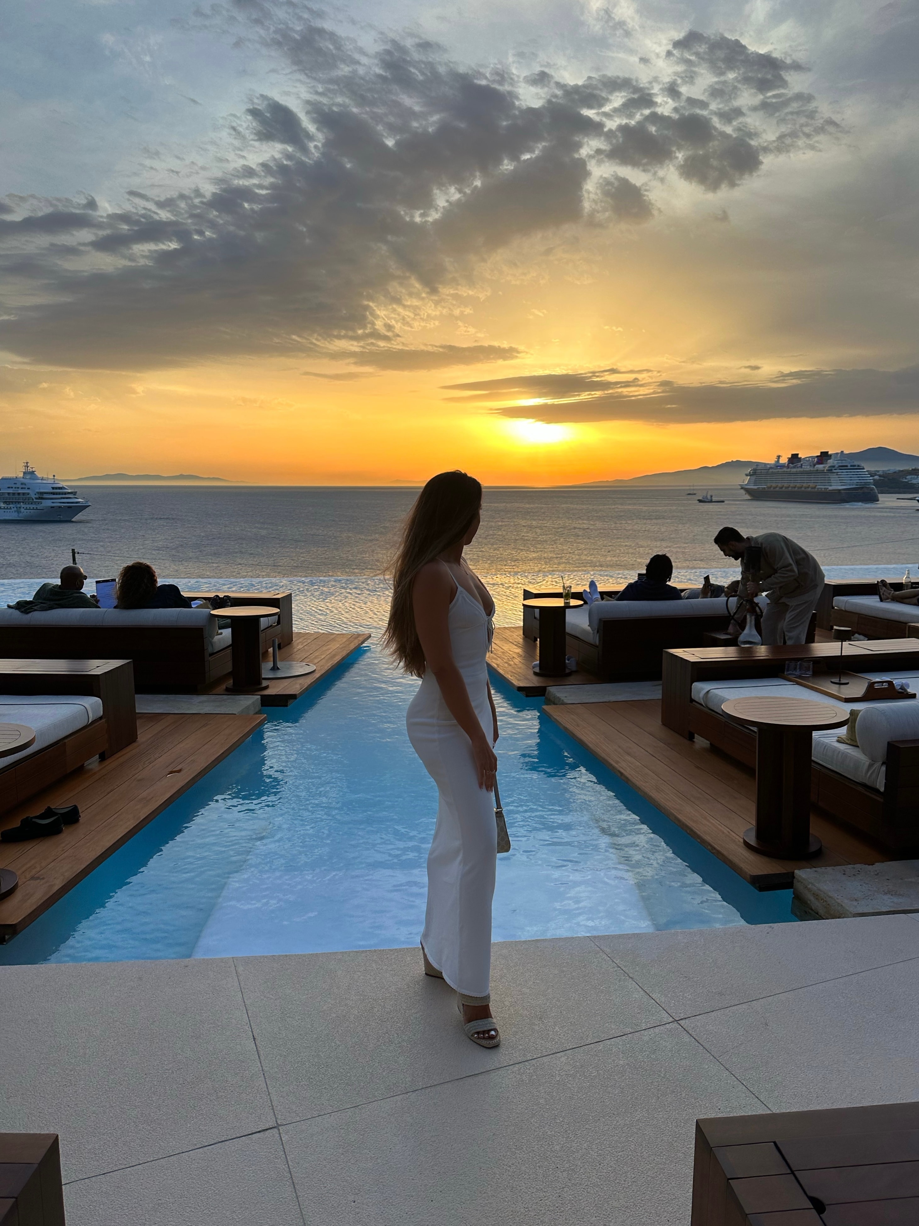 Advisor posing in front of an infinity pool with an ocean view at sunset. 