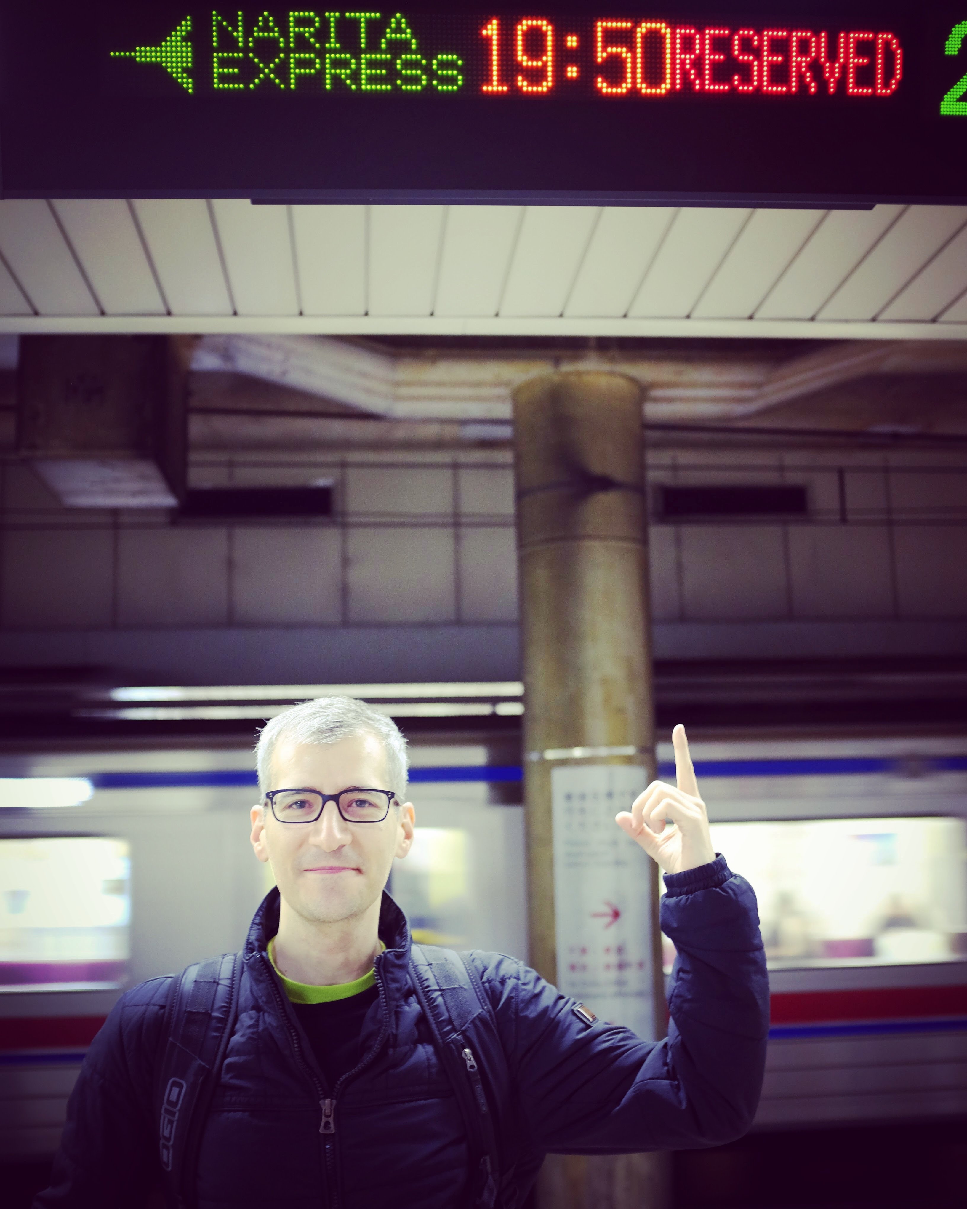 Advisor standing under a neon sign with a station in the distance. 