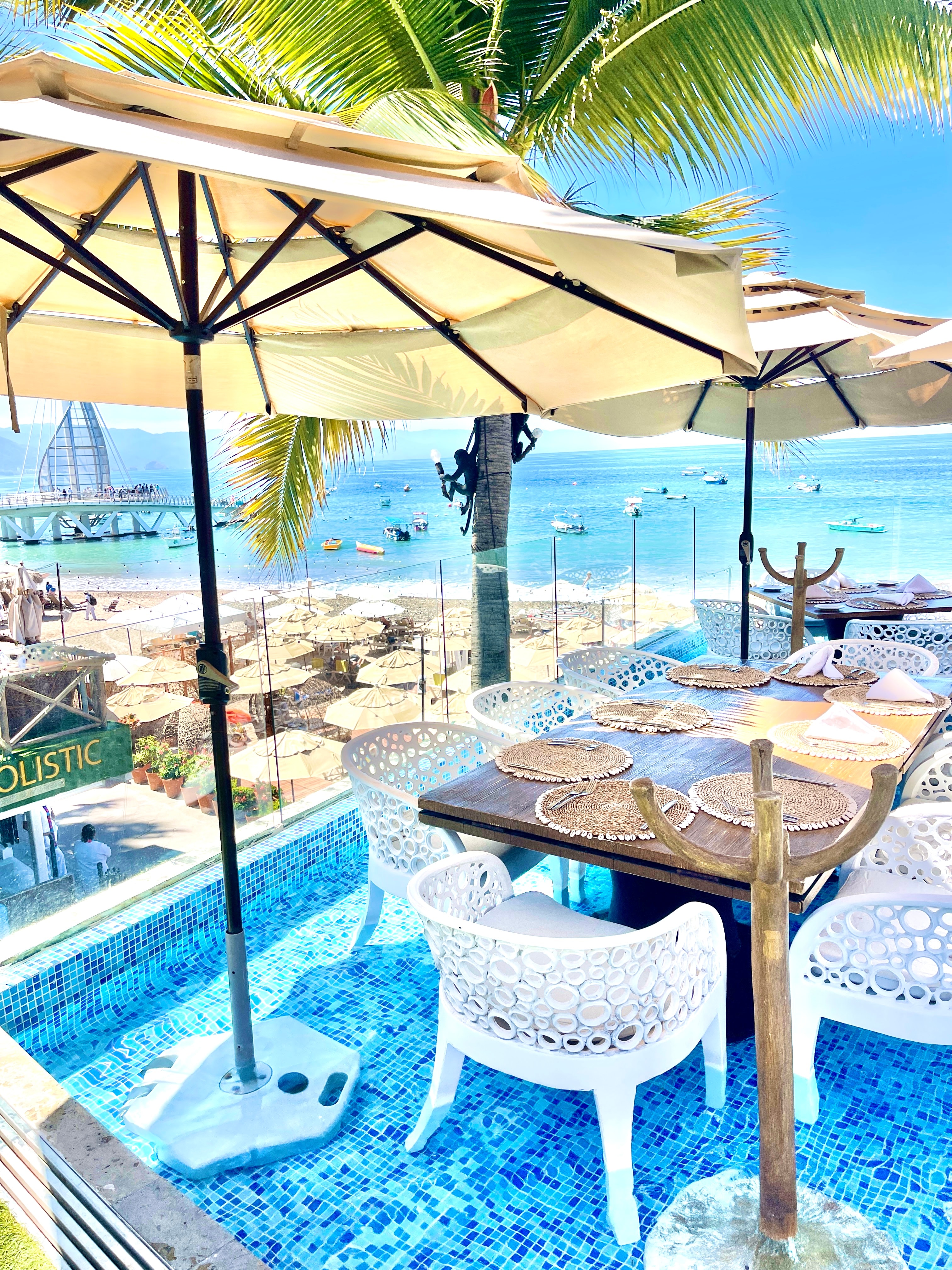 A table setting outside with the ocean in the distance on a sunny day.