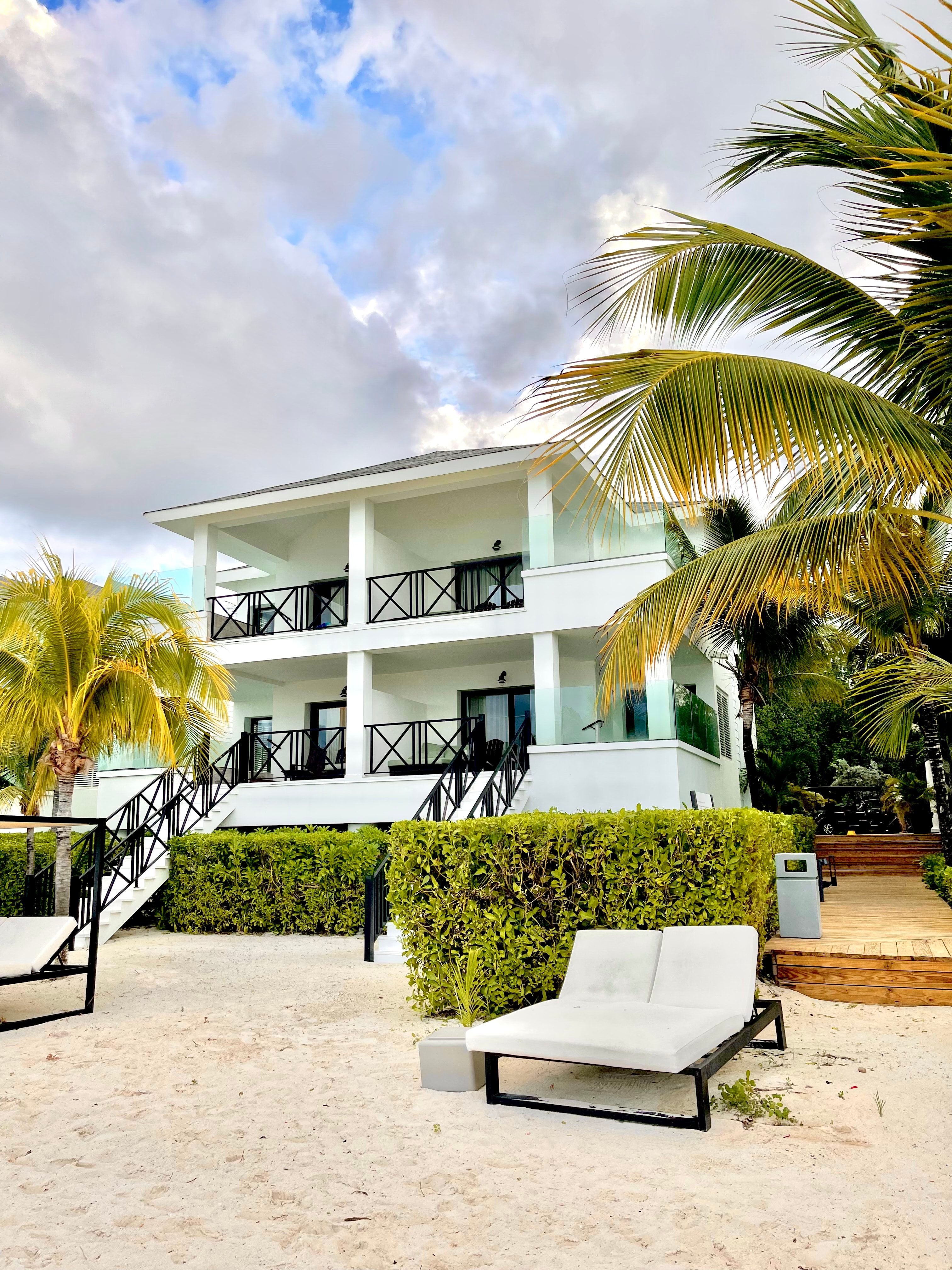 A view of a villa with a seating area and foliage during the daytime.