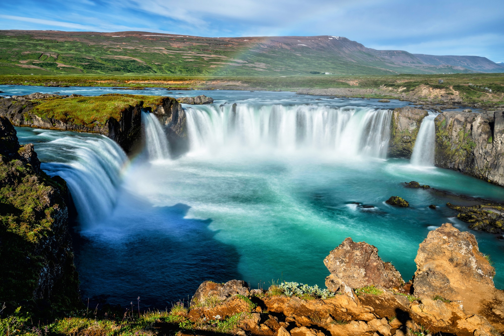 Beautiful aerial view of a massive waterfall surrounded by mountains on a sunny day