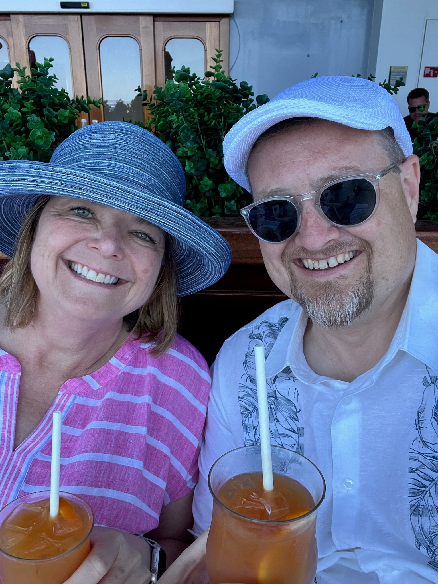 Photo of advisor and partner with hats on posing with drinks in hand. 