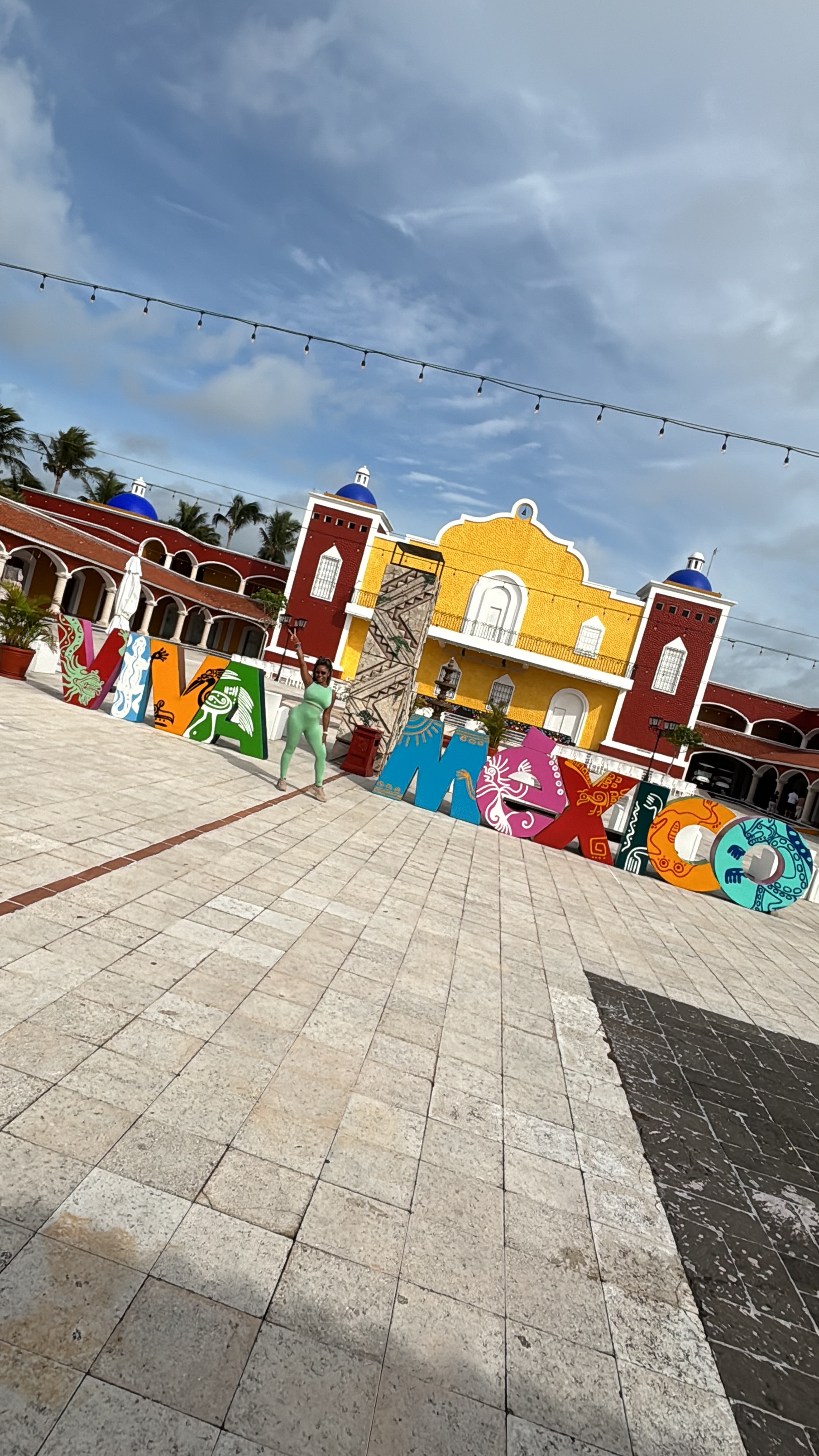 View of a colorful sign in an empty plaza reading “Viva Mexico” under sunny skies