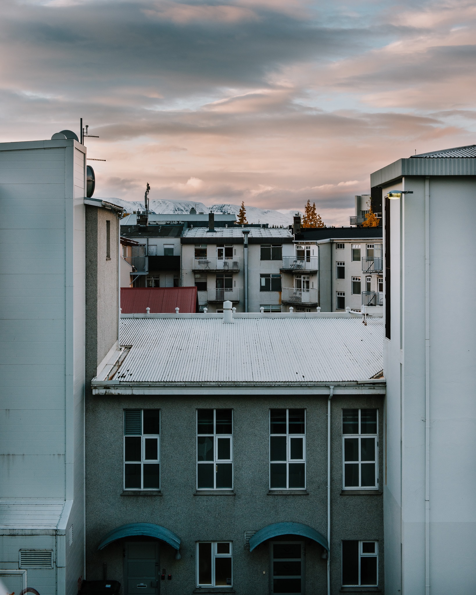 Pretty view of the rooftops of several white buildings under cloudy skies at sunset