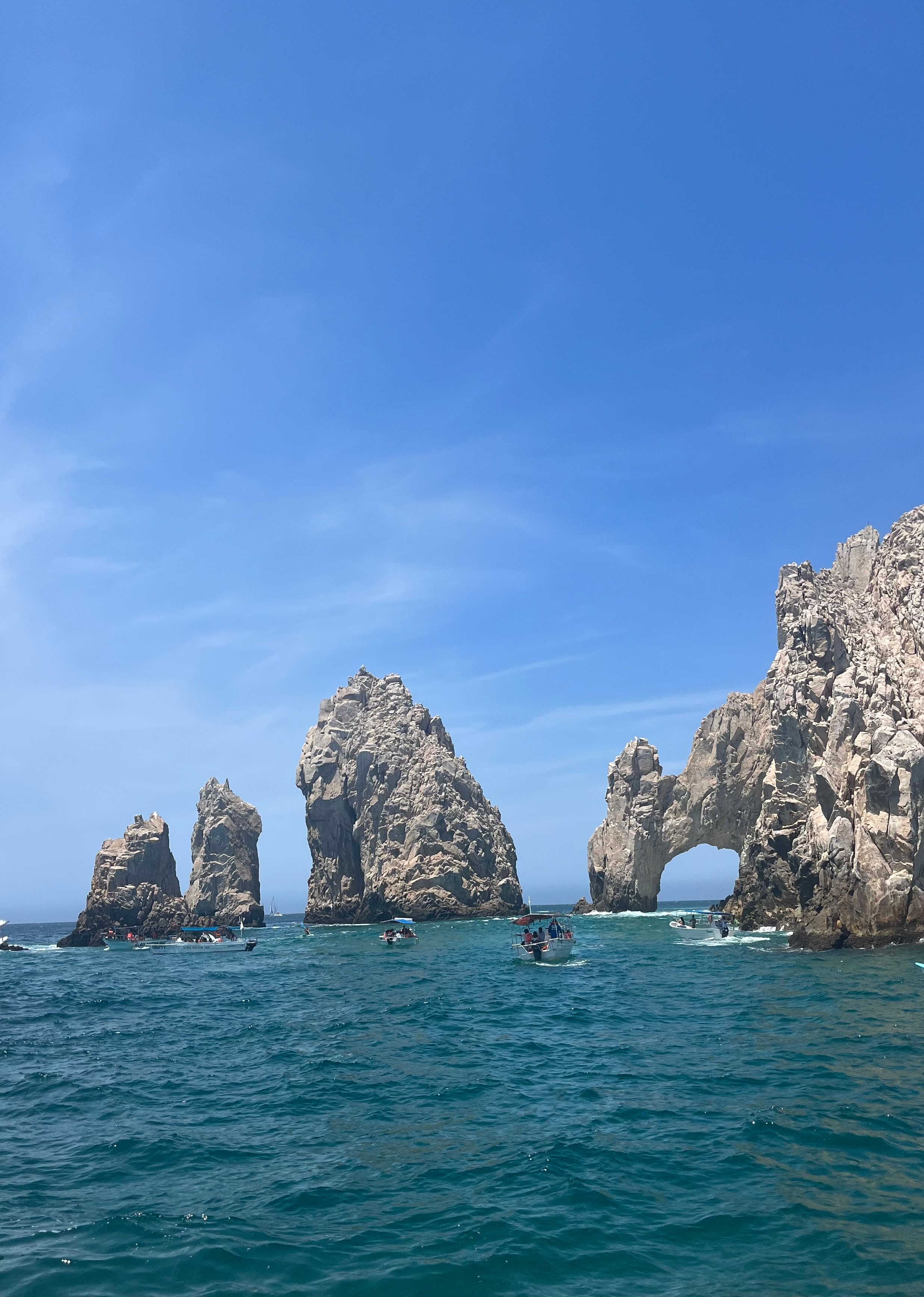 Large rock formations and a rock archway sticking out of a deep blue ocean.