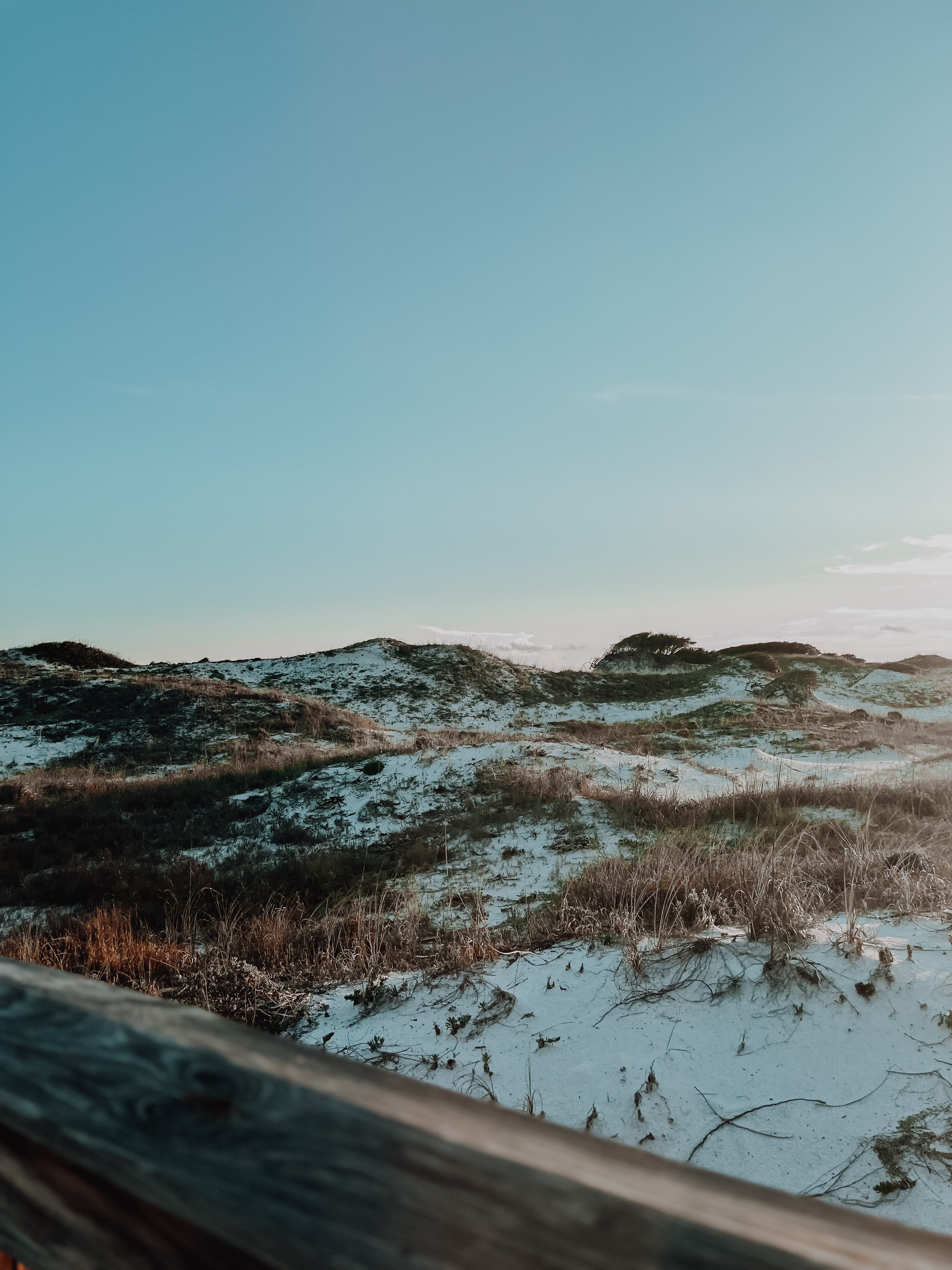 white rollings hills with brown grasses and a blue sky at dusk.