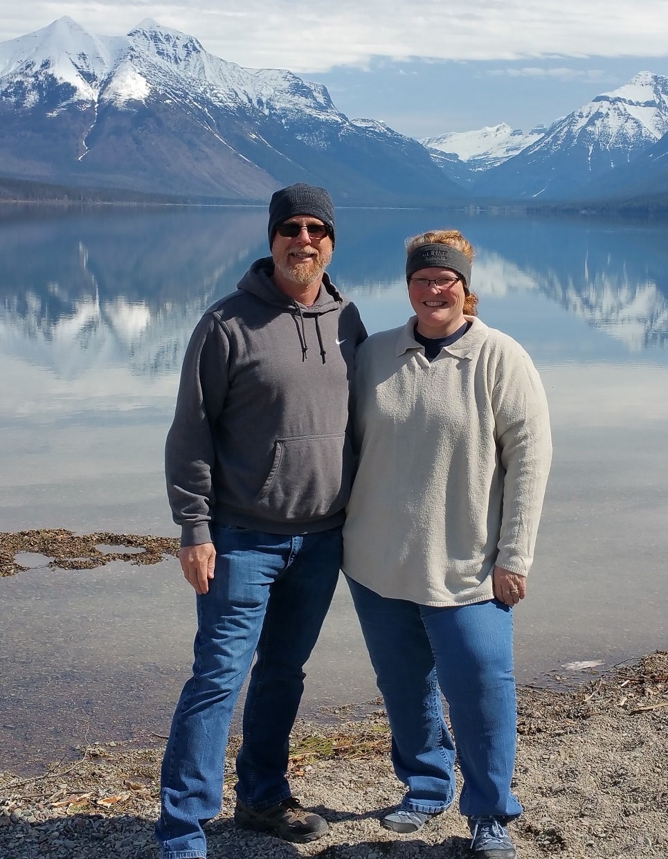 Ashley and her partner with their arms around each other in front a beautiful winter lake with snowy mountains visible in the distance