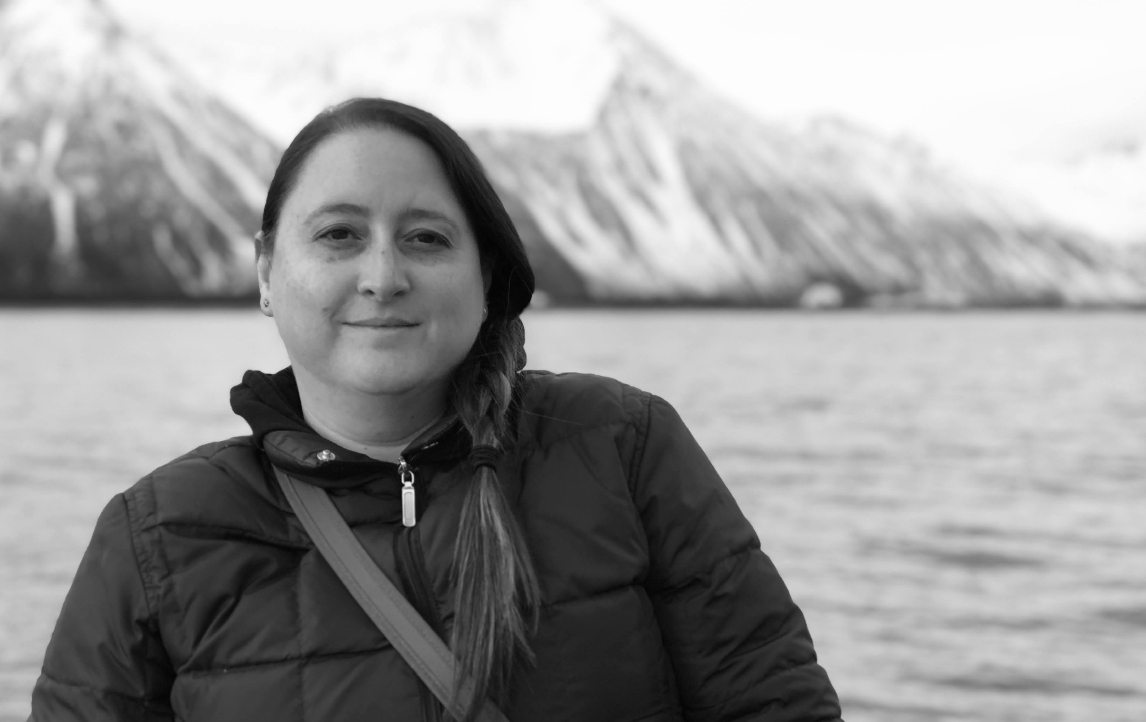 Advisor posing for an image with a mountain range and the ocean in the distance. 