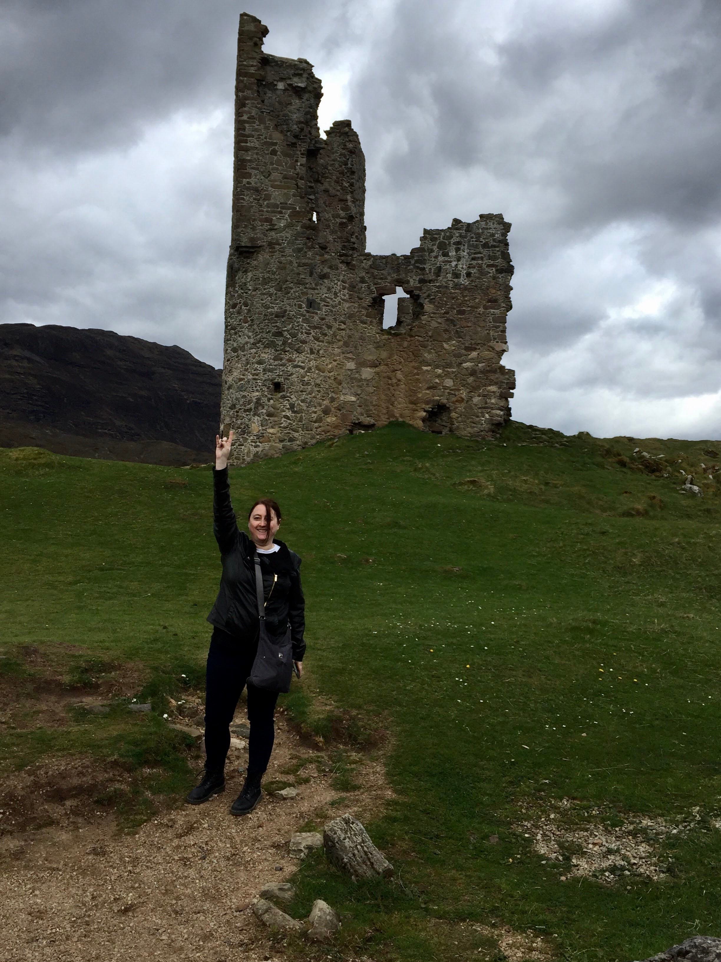 Advisor posing with ancient ruins in the distance on a cloudy day. 