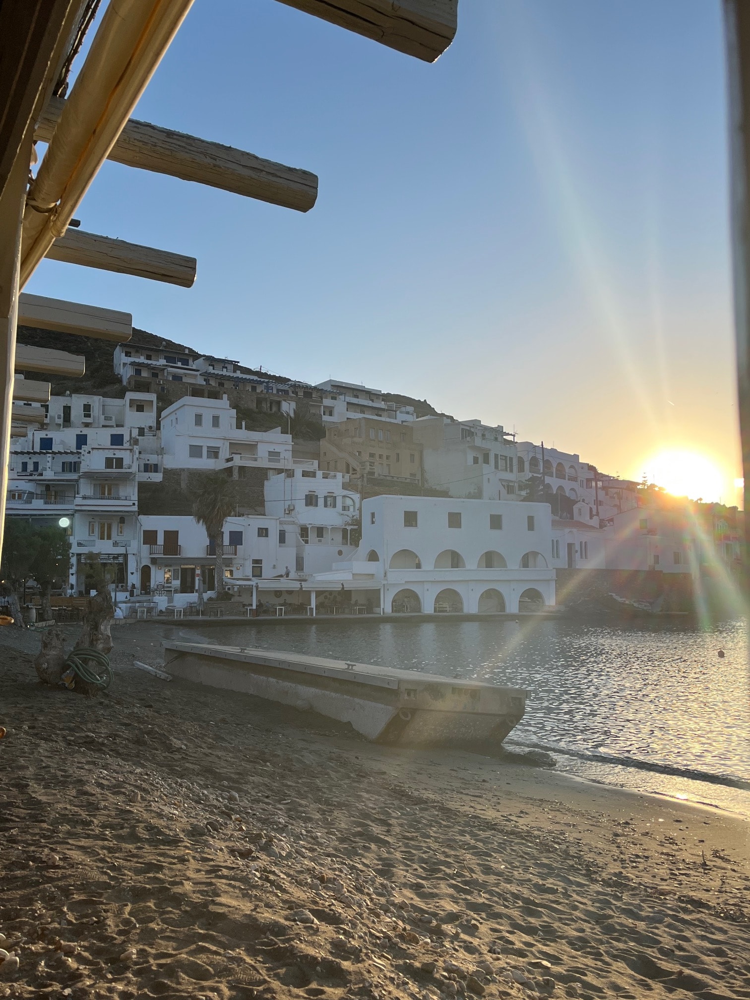 Beautiful view of an empty beach at sunset with small buildings on the coastline behind it