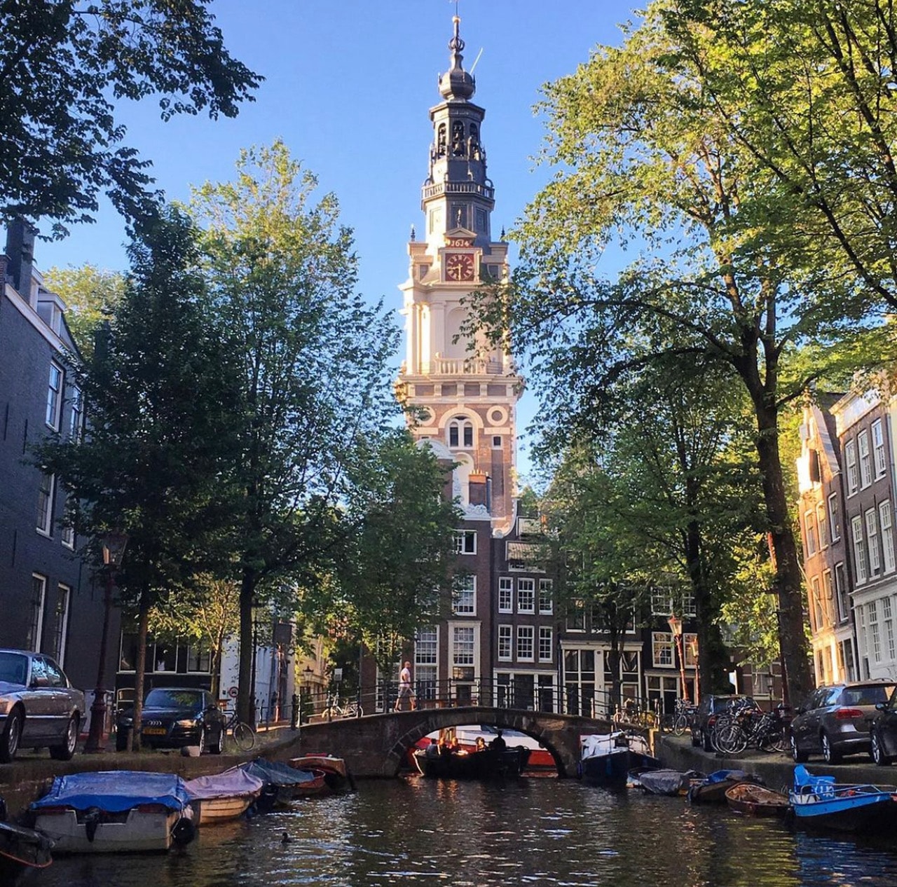 Beautiful view of a canal in Amsterdam with a church visible in the distance on a sunny day