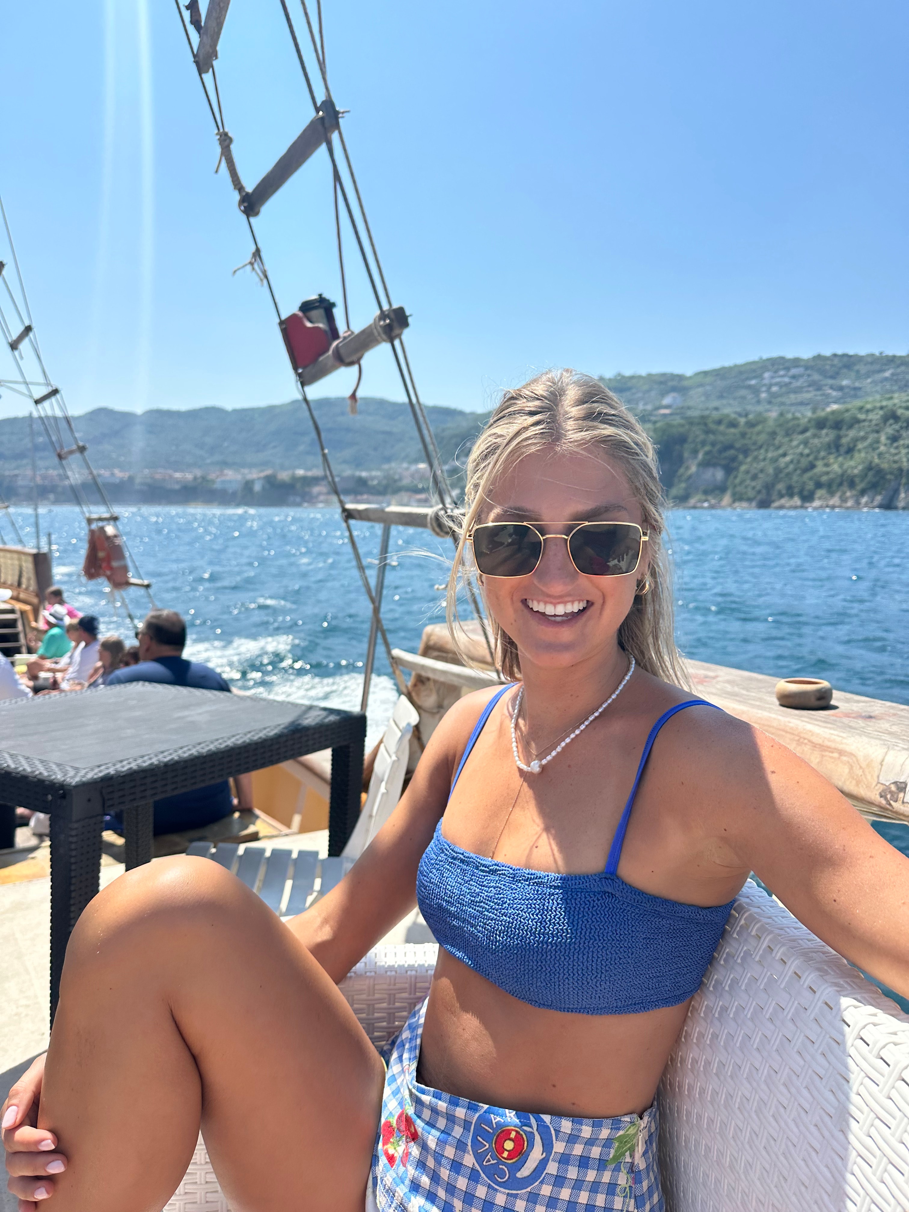 Hannah in a blue top and sunglasses enjoying the sun on a boat out to sea