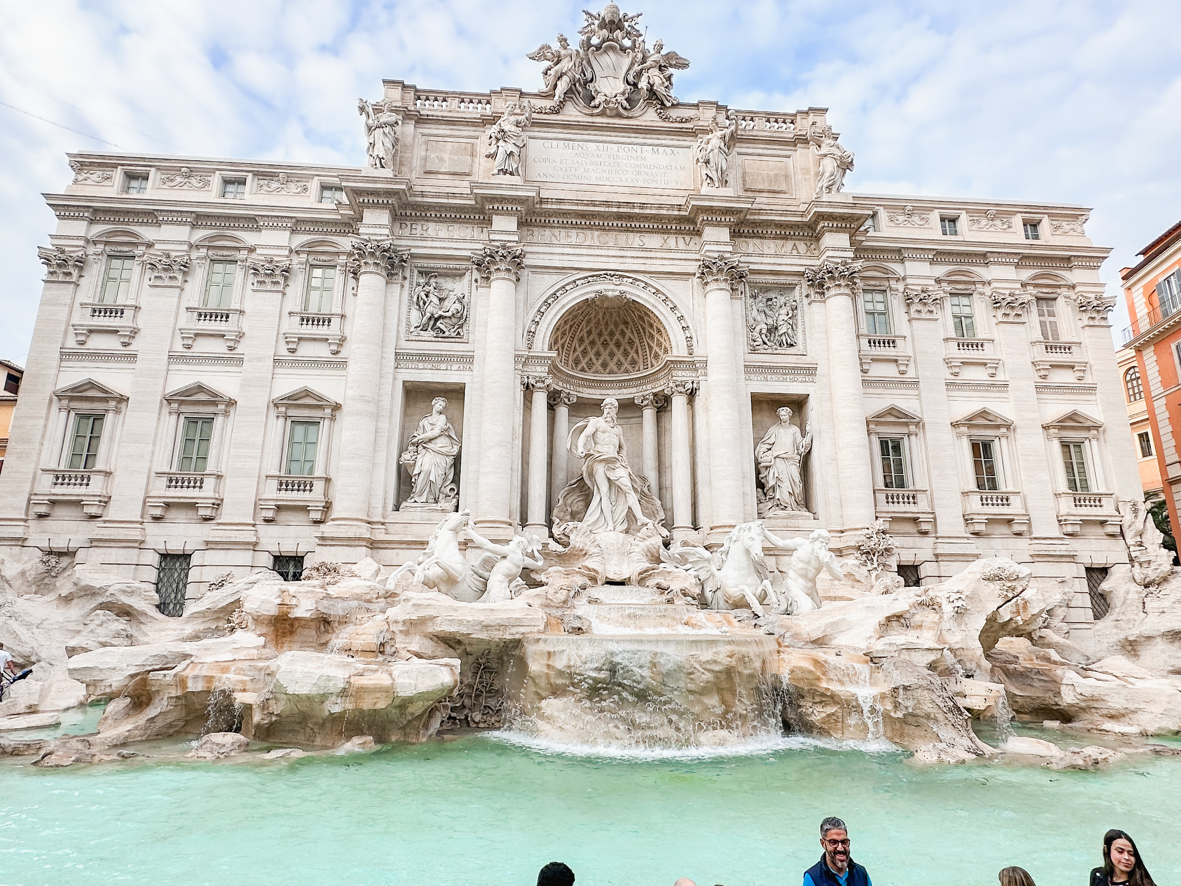 A large stone historical building with elaborate statues and water surrounding it.