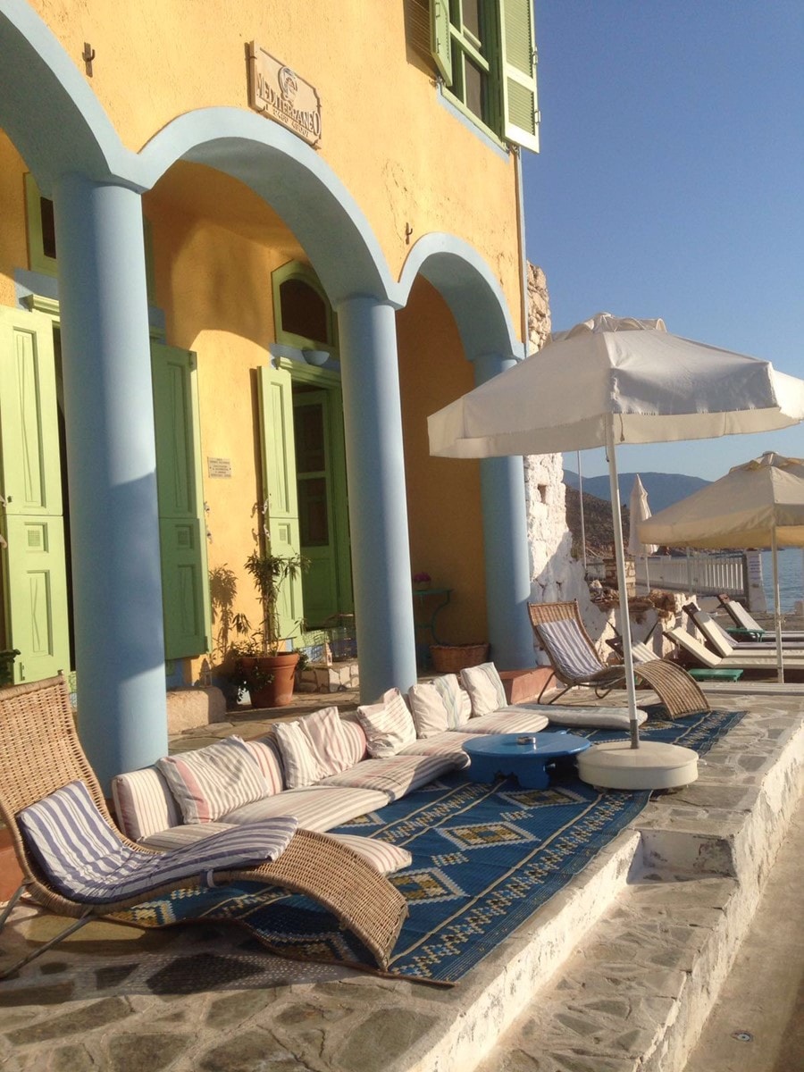 Beautiful view of lounge chairs and cushions near a yellow building on a sunny day