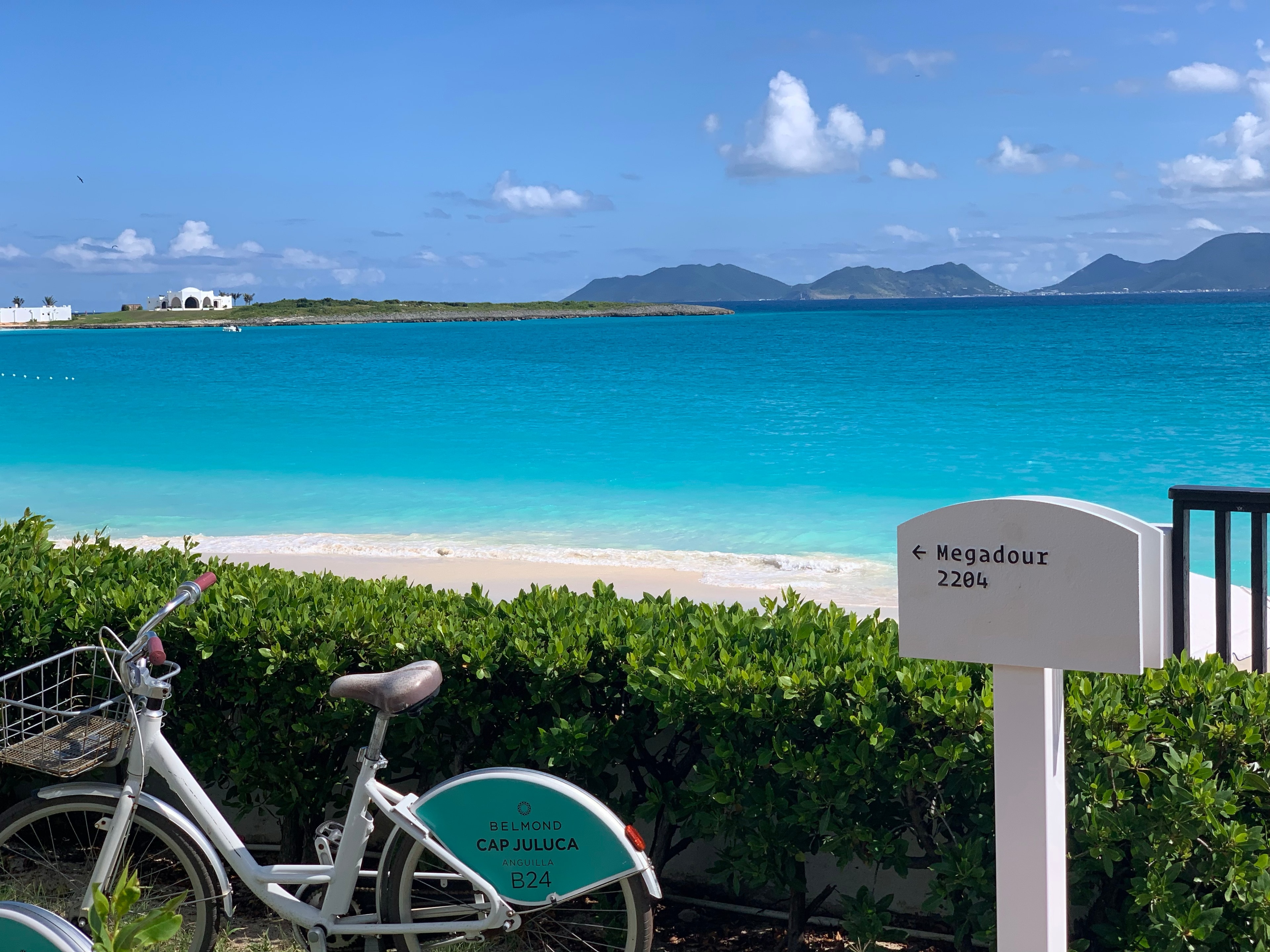 View of a bike from Cap Juluca resort parked by a beautiful white sand beach and turquoise sea