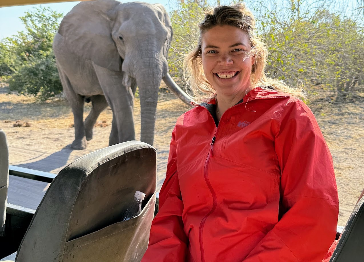 Advisor inside a safari vehicle posing for a photo with an elephant visible behind her