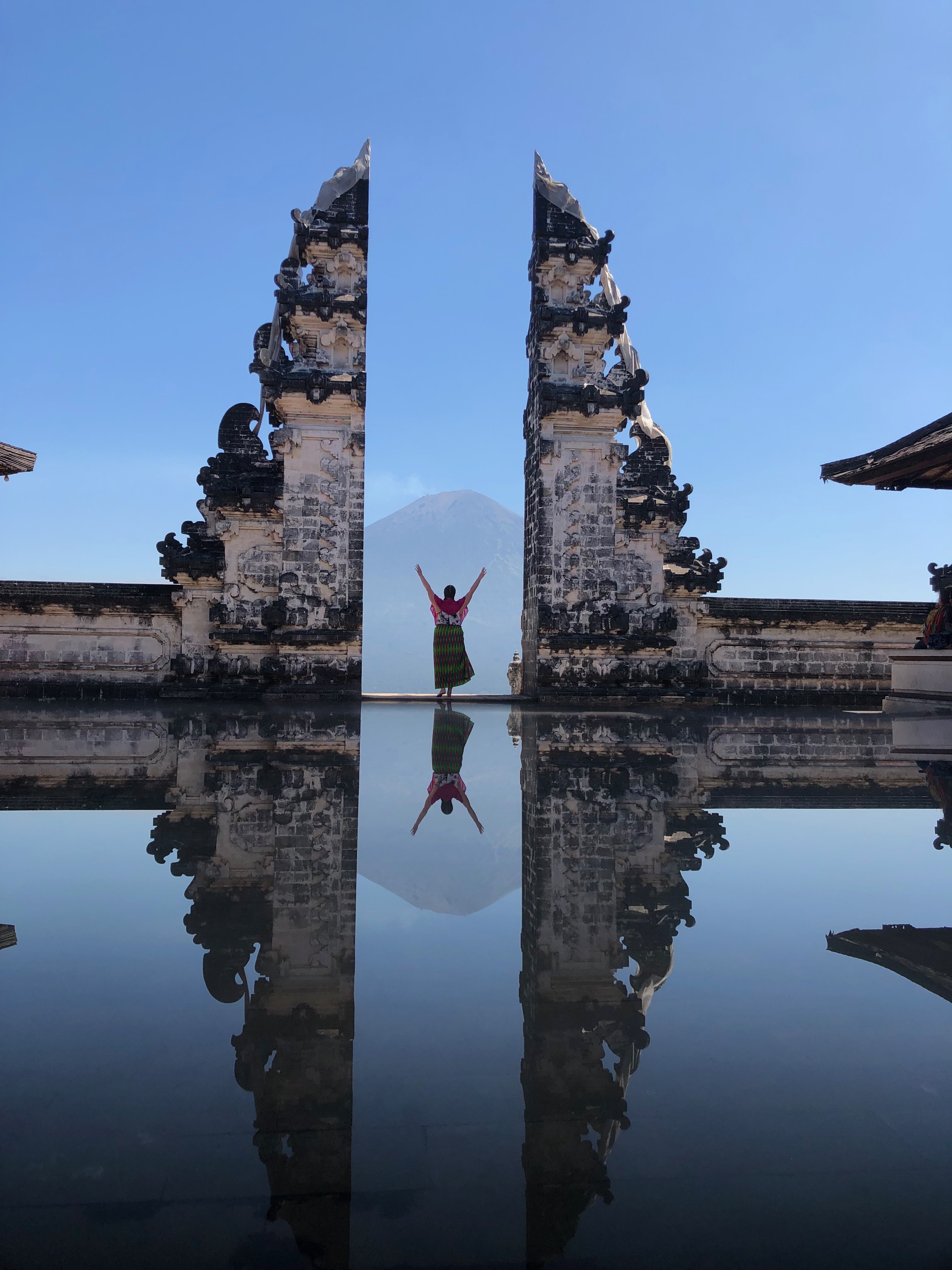 View of advisor posing by a glassy pond in between the ruins of a stone wall on a clear day