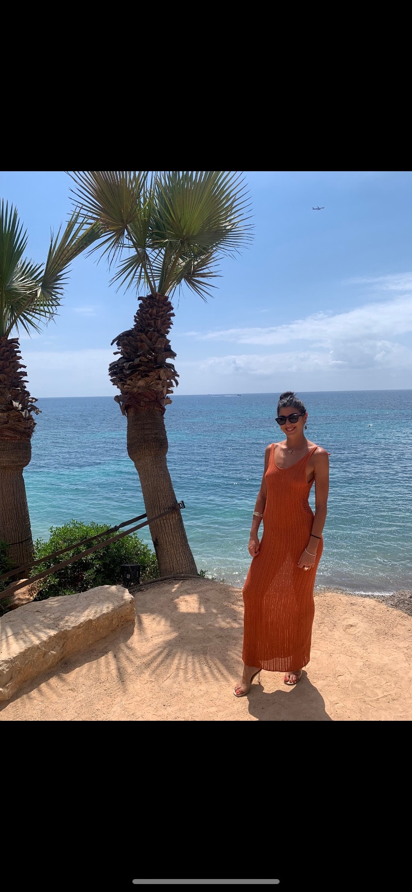 Advisor posing nest to palm trees in a sandy beach. 