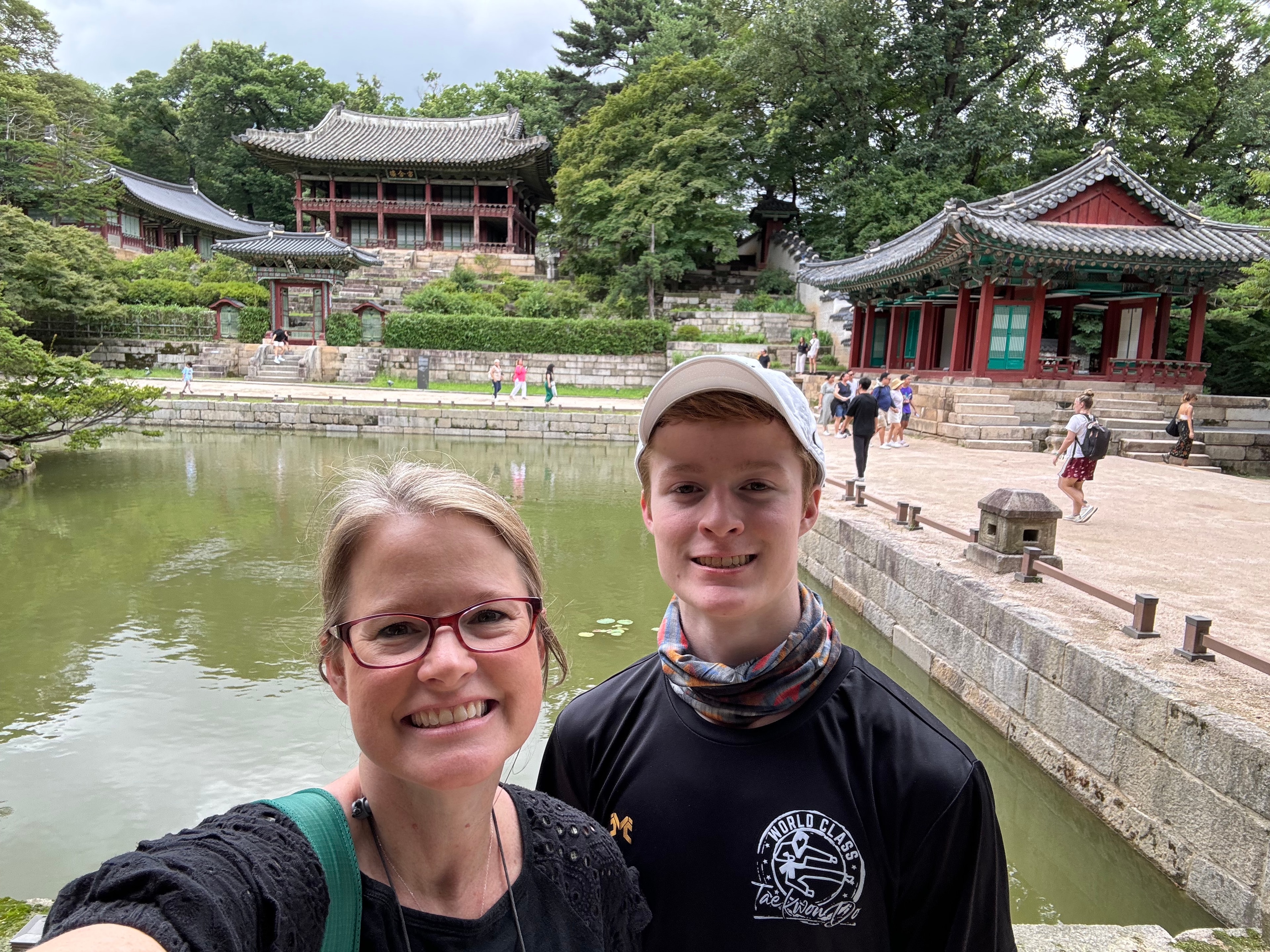 Advisor taking a selfie with a young boy in front of a temple-like building and lake