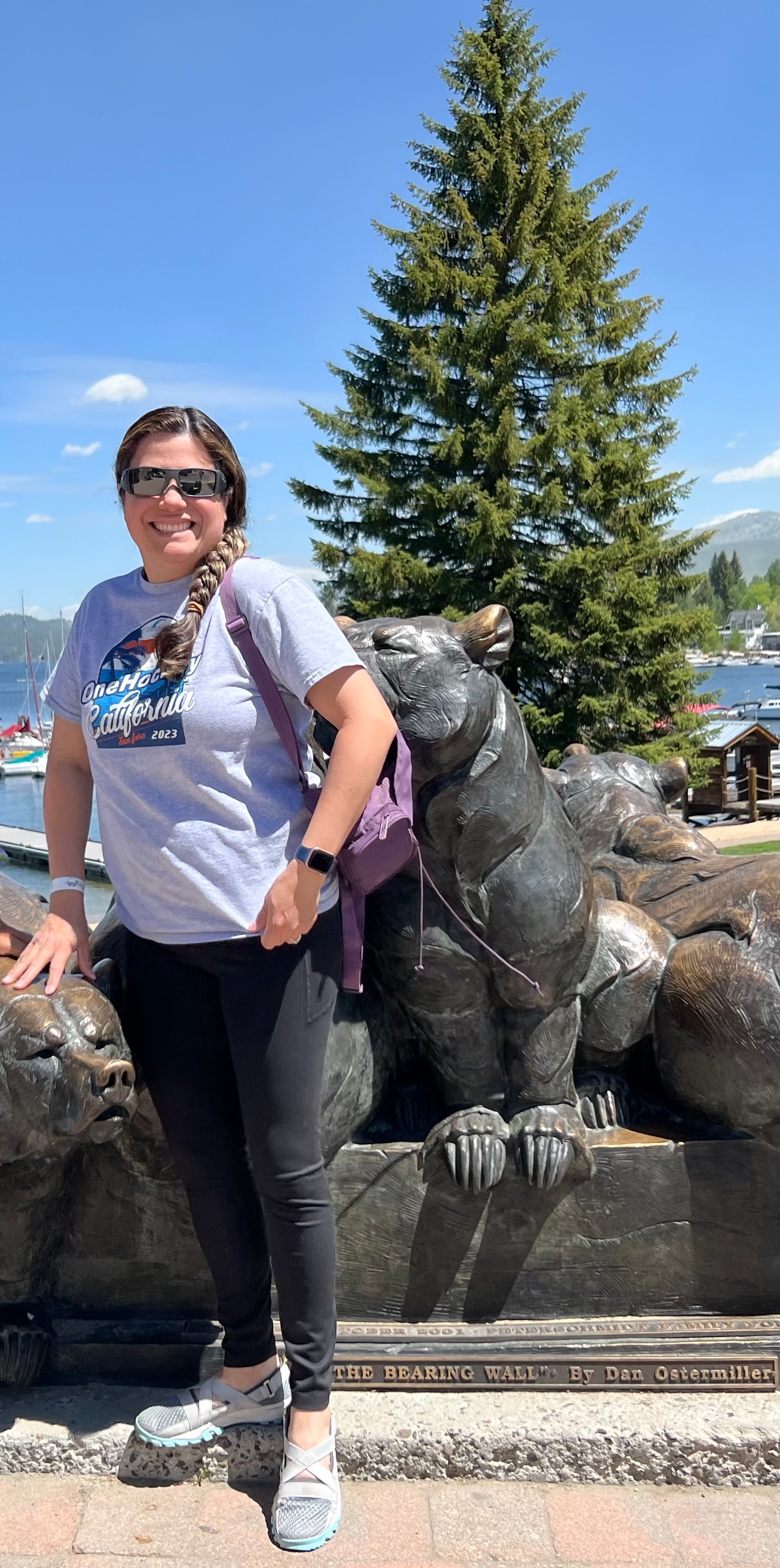 Advisor posing outdoors in front of the statue of a bear and large pine tree