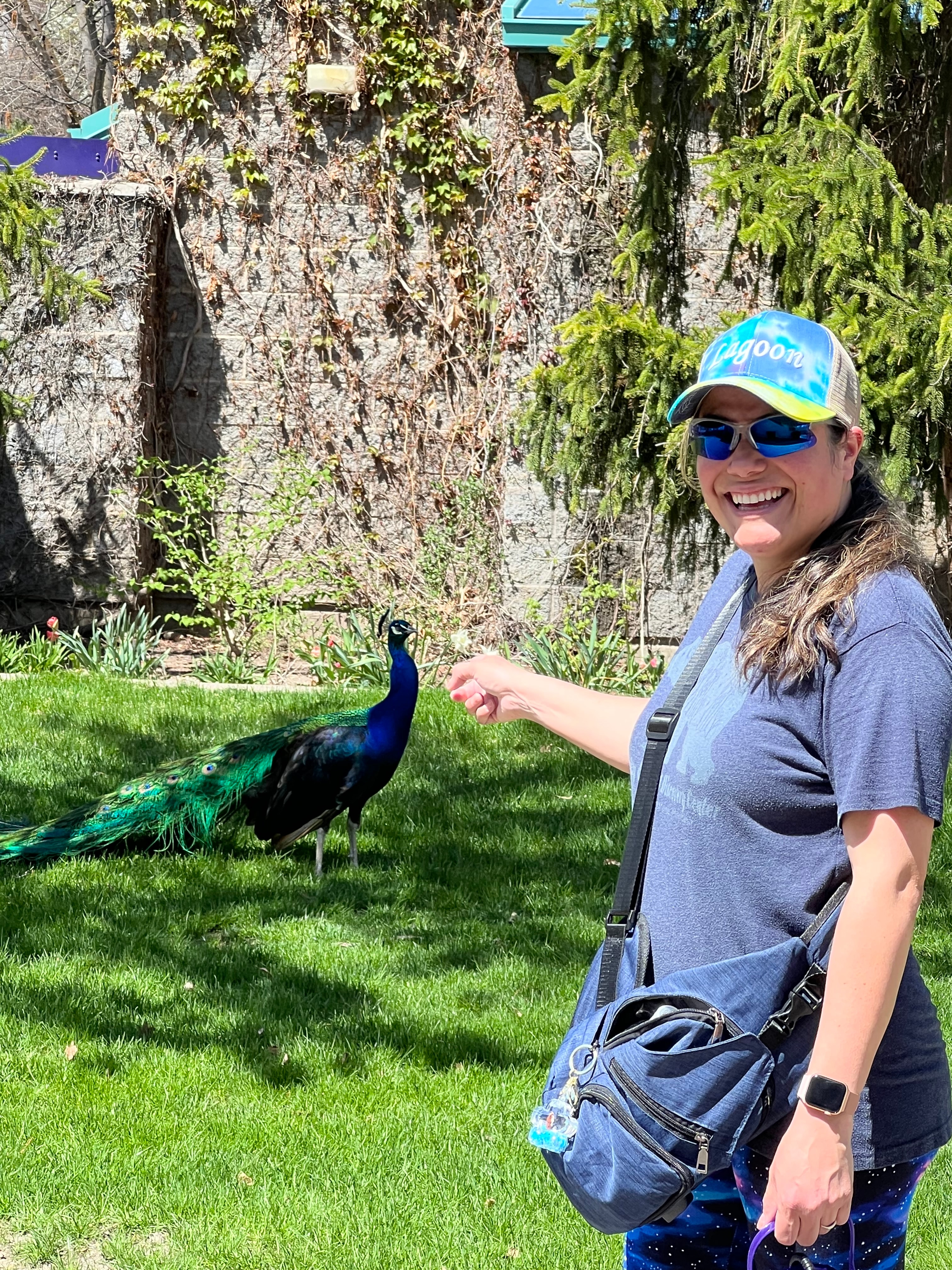 Advisor smiling for a photo outdoors in a grassy area with a peacock visible in the background