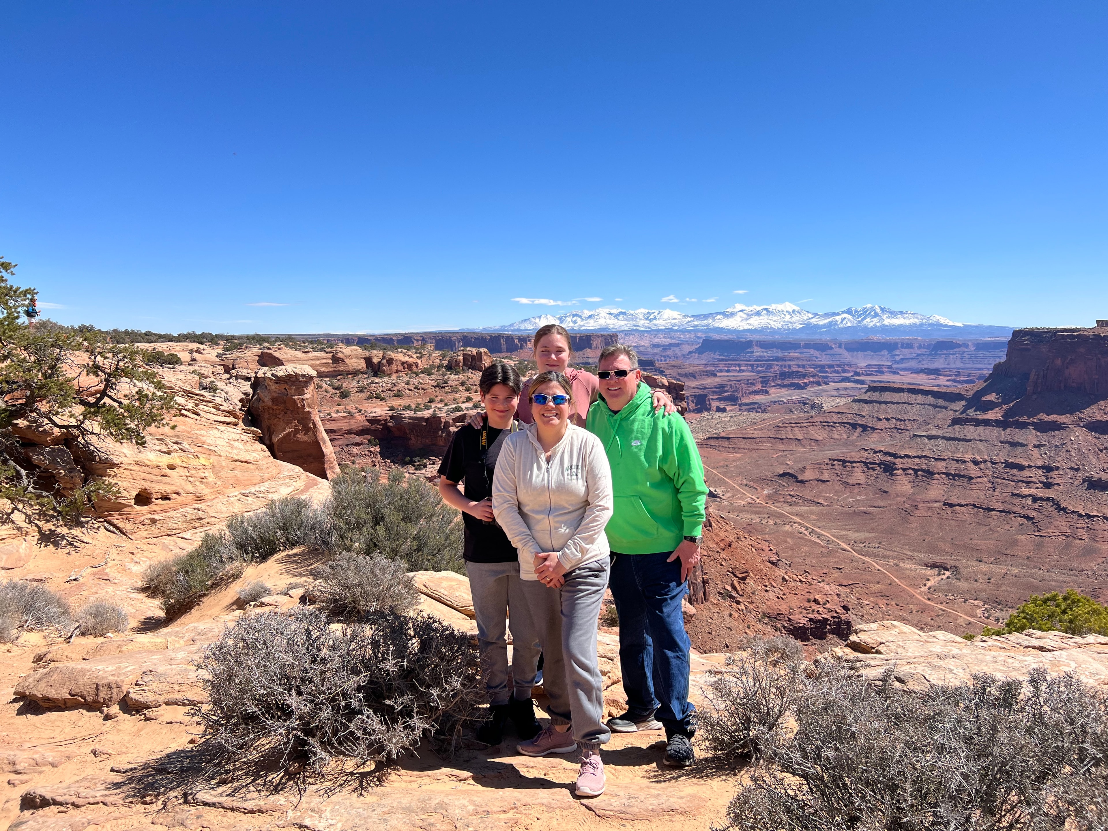 Evelyn and her family posing for a photo overlooking a large canyon on a sunny day