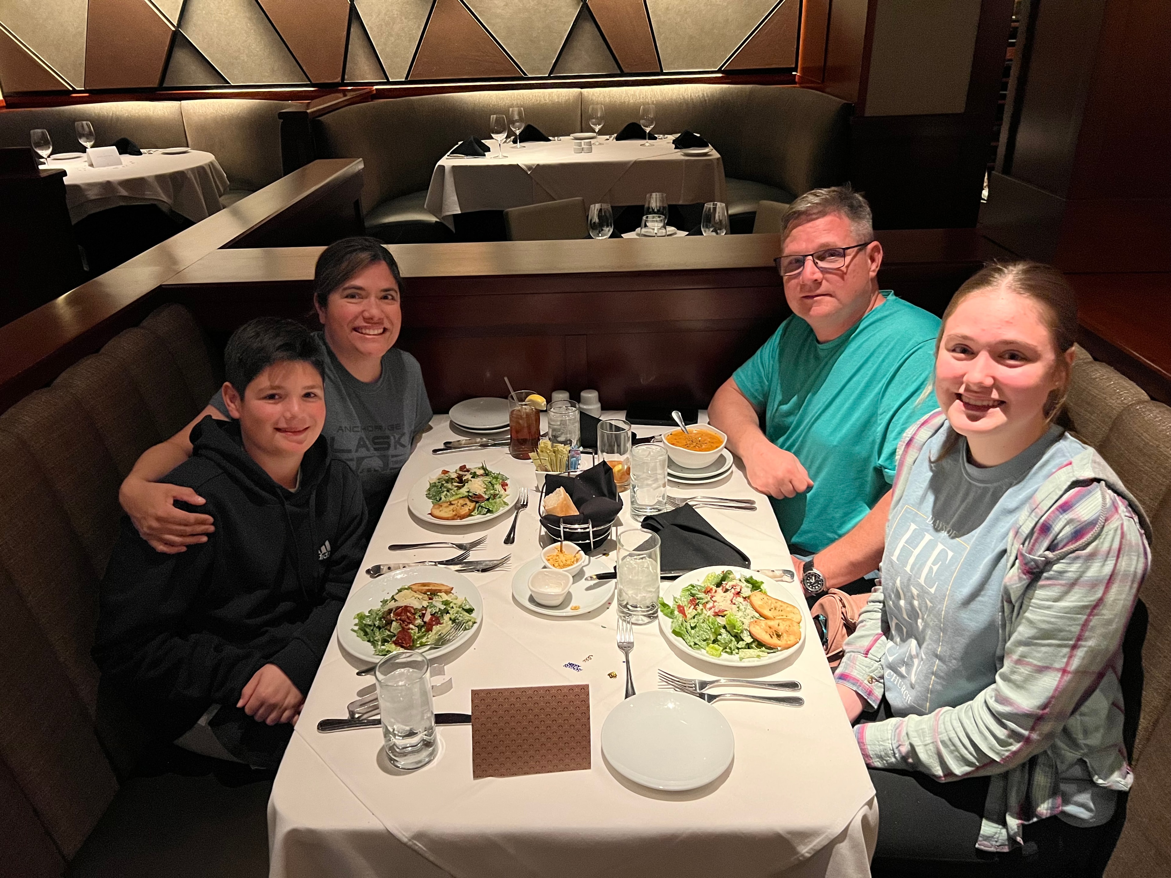 Advisor and her family smiling for a photo in a restaurant booth with plates of food in front of them