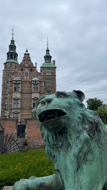 A green statue in front of a red brick building.