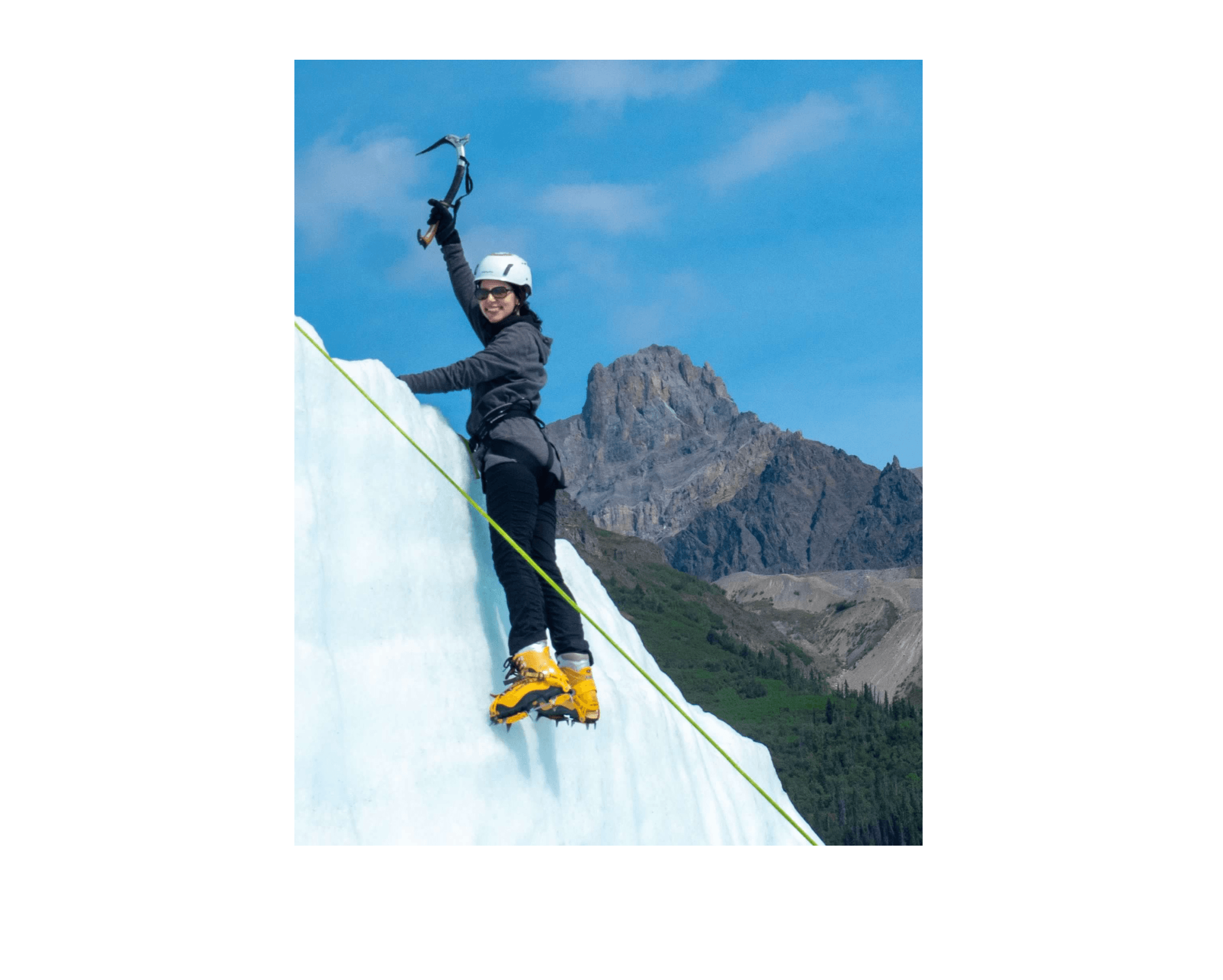 View of advisor holding an ice pick while scaling a glacier