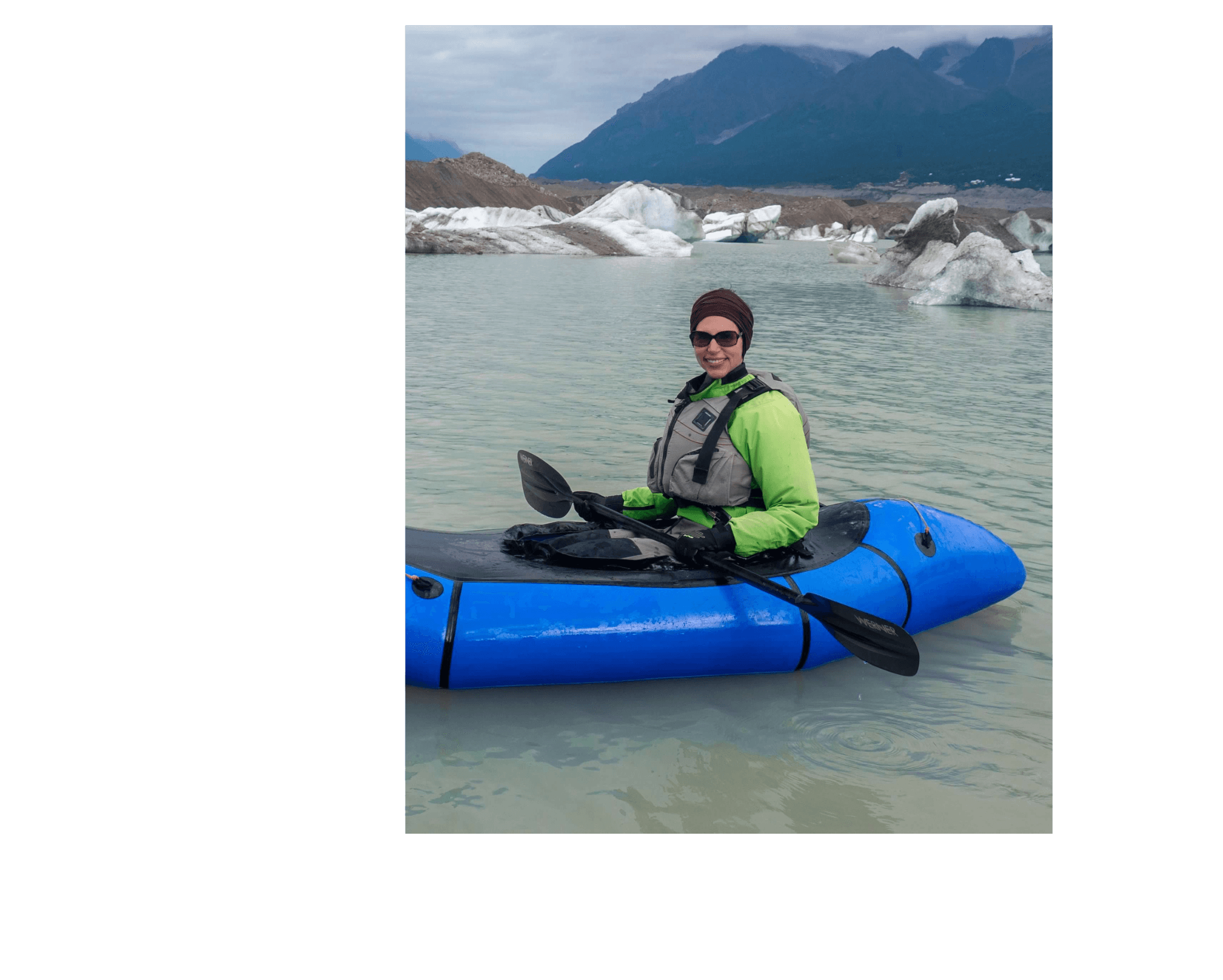 Advisor holding an oar in a blue kayak in an Arctic environment