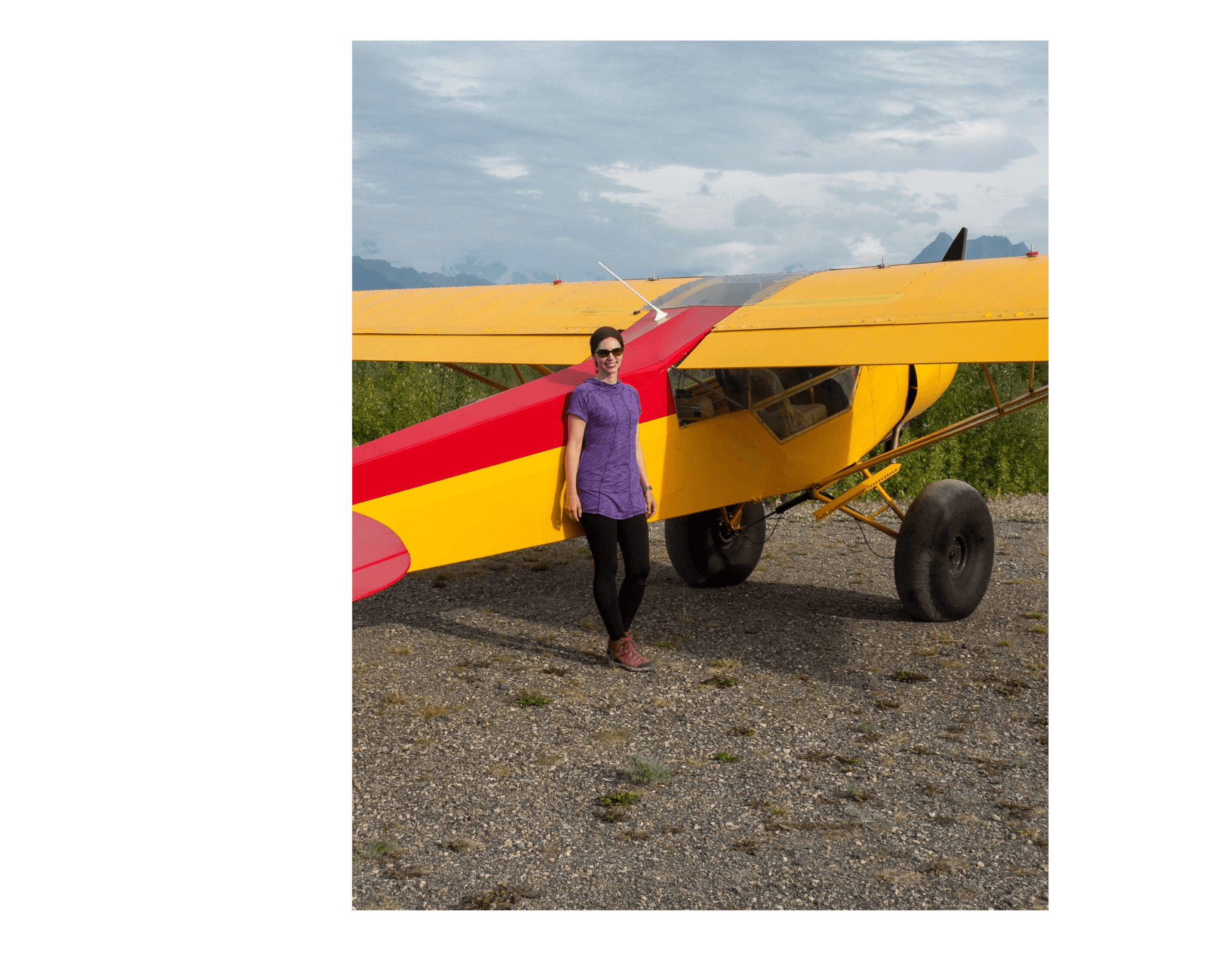 Advisor in a purple shirt standing by an old-fashioned yellow and red Advisor in a purple shirt standing by an old-fashioned yellow and red propeller plane plane