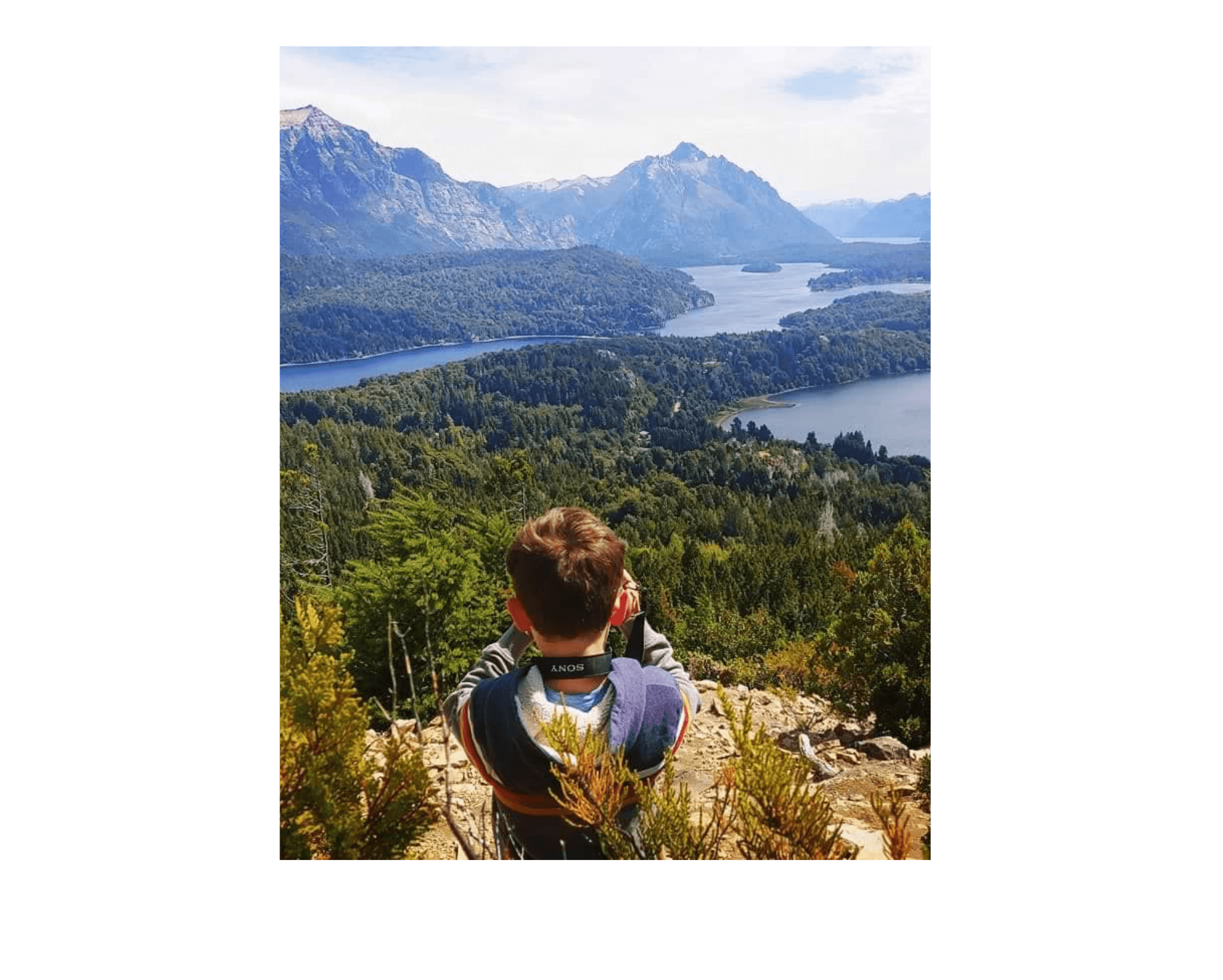 View of a young boy at a lookout point with a beautiful forest and lake landscape before him