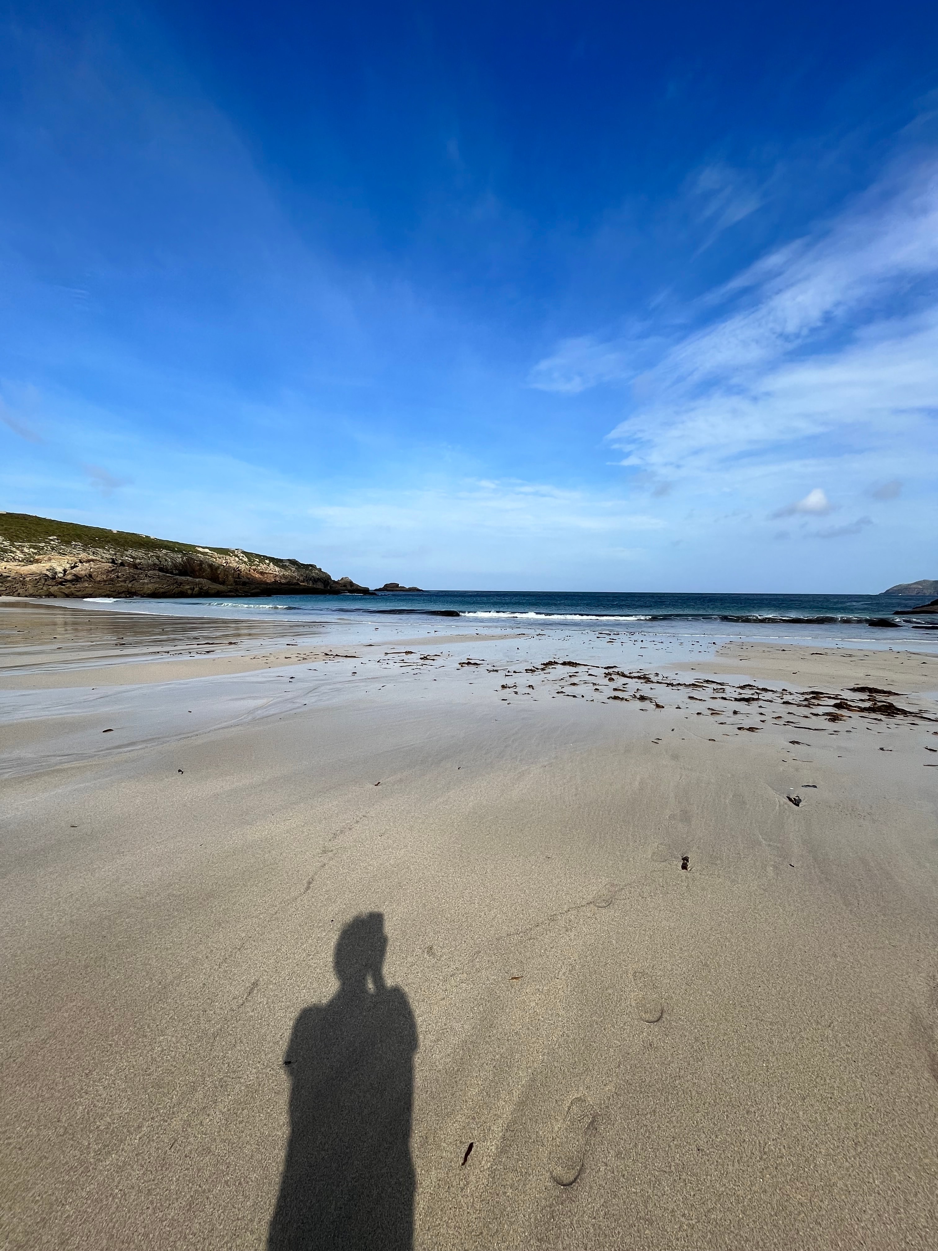 View of advisor’s shadow taking a photo of an empty beach under sunny skies