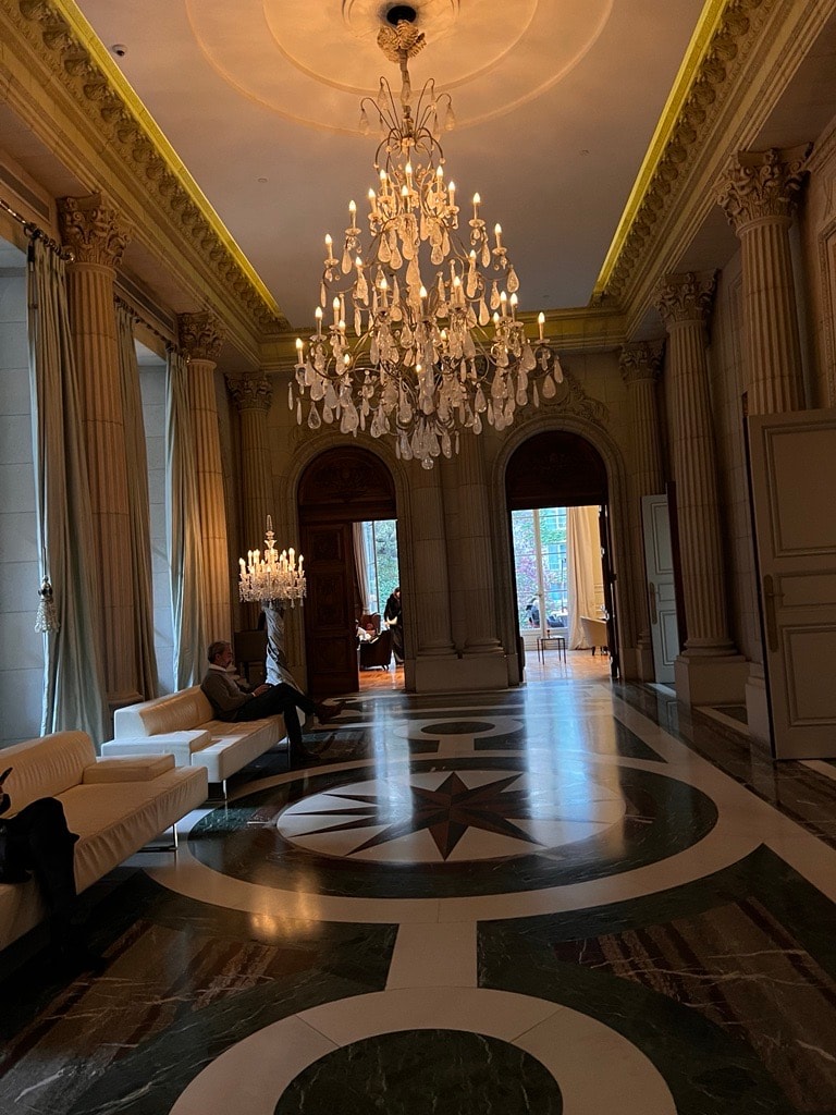 View of an empty grand hall with large chandelier and marble floors