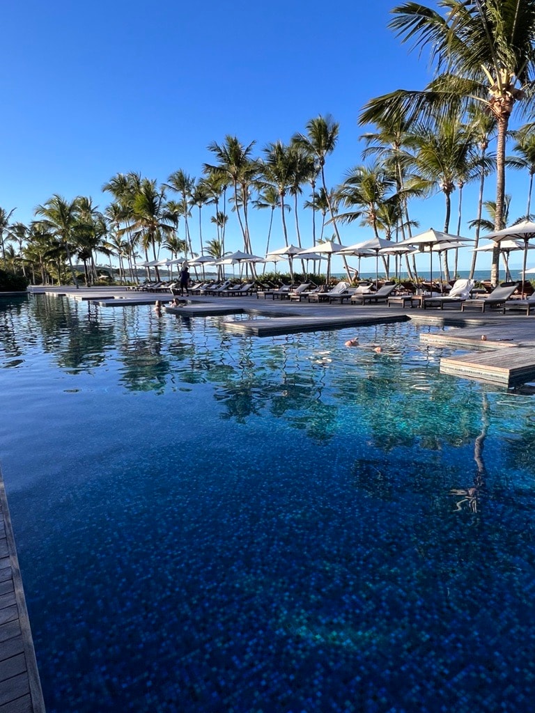 View of a beautiful resort pool on a clear day with lounges in shallow water